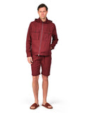 Man wearing a maroon tracksuit on a white background