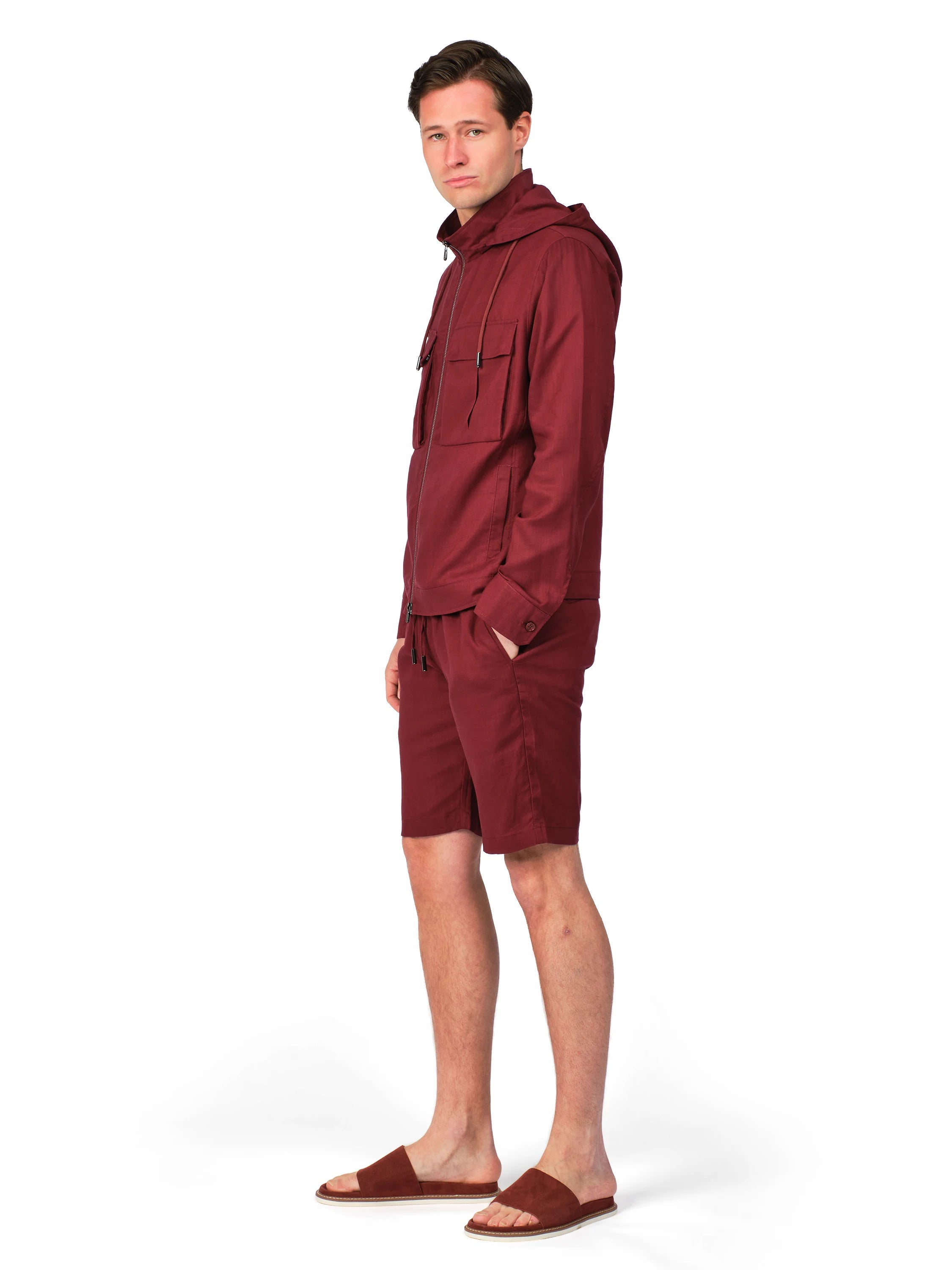 Man wearing a maroon raincoat and shorts on a white background