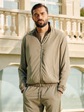 Man wearing a beige tracksuit standing in front of a building with columns.