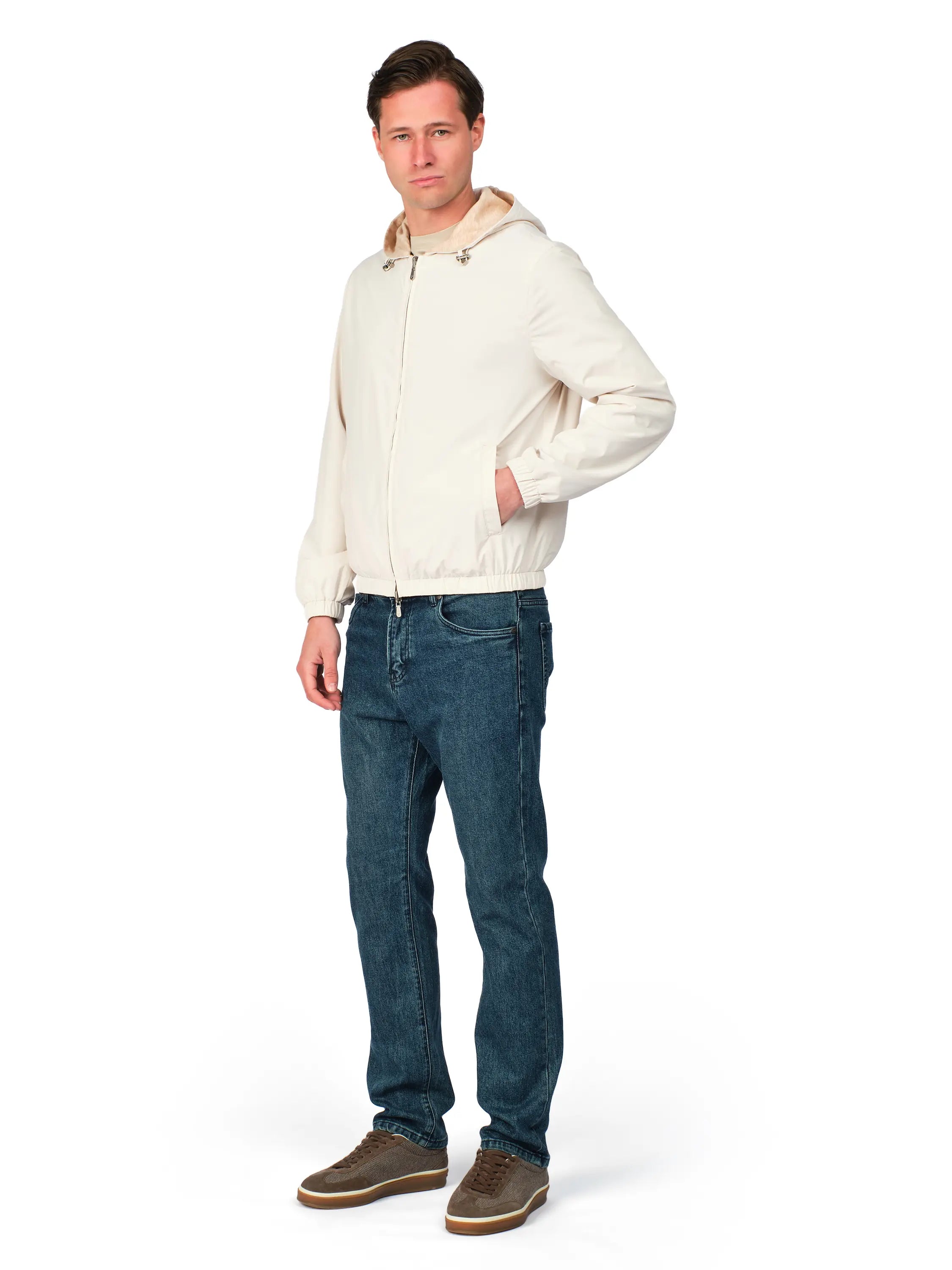 Man wearing a beige jacket and blue jeans on a white background