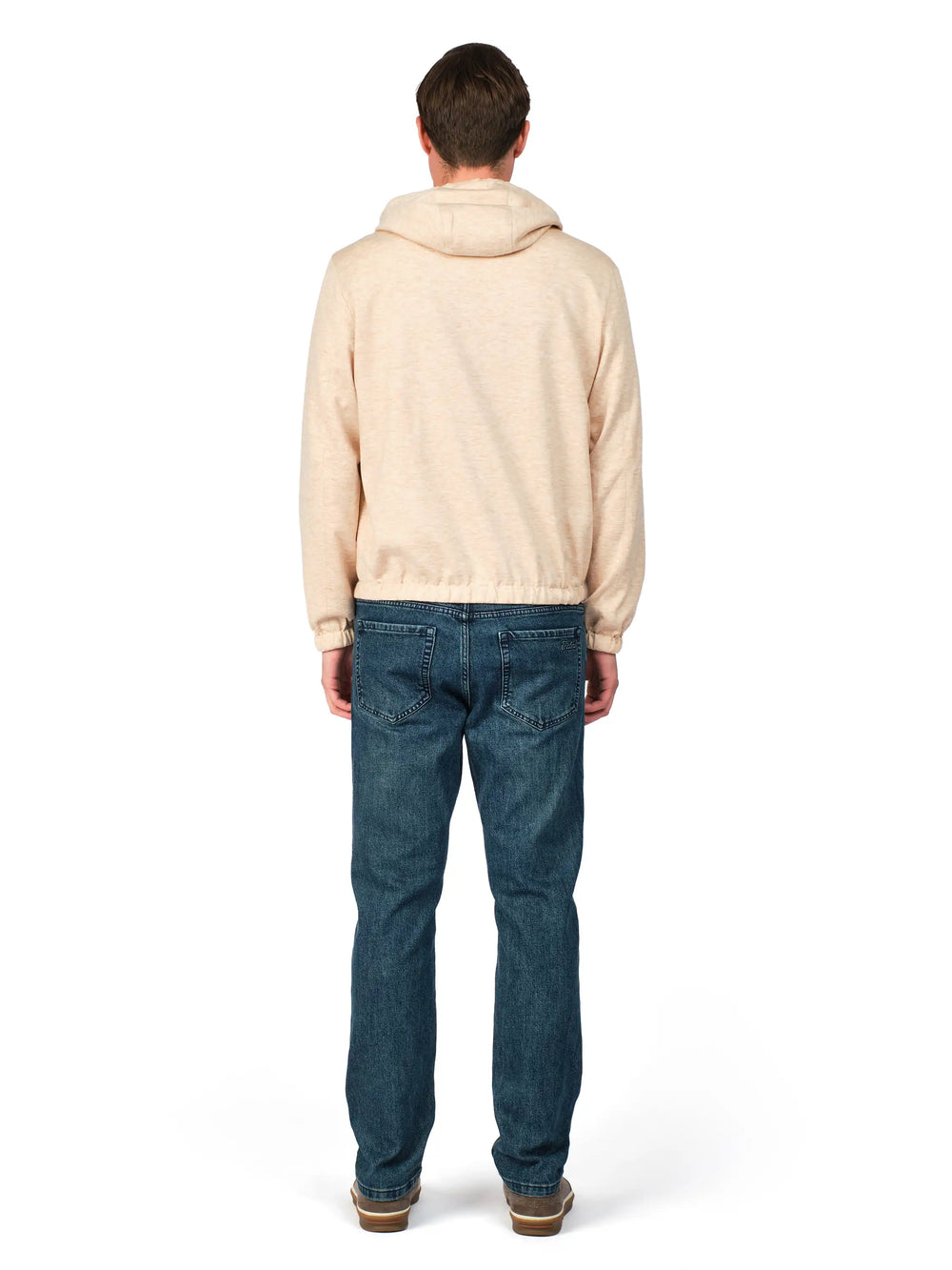 Person wearing a beige hoodie and blue jeans on a white background