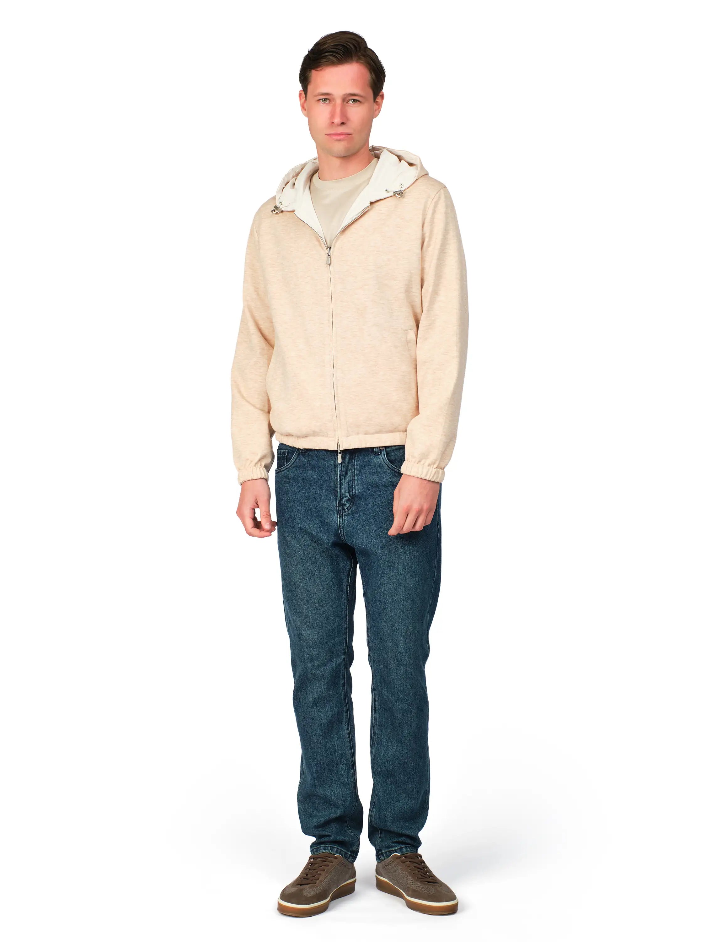 Man wearing a beige hoodie and blue jeans on a white background