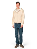 Man wearing a beige hoodie and blue jeans on a white background
