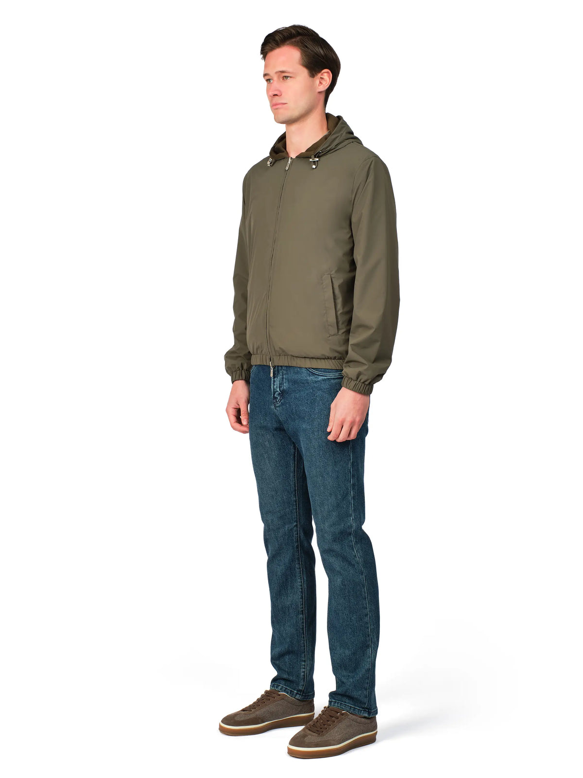 Man wearing a green jacket and blue jeans on a white background
