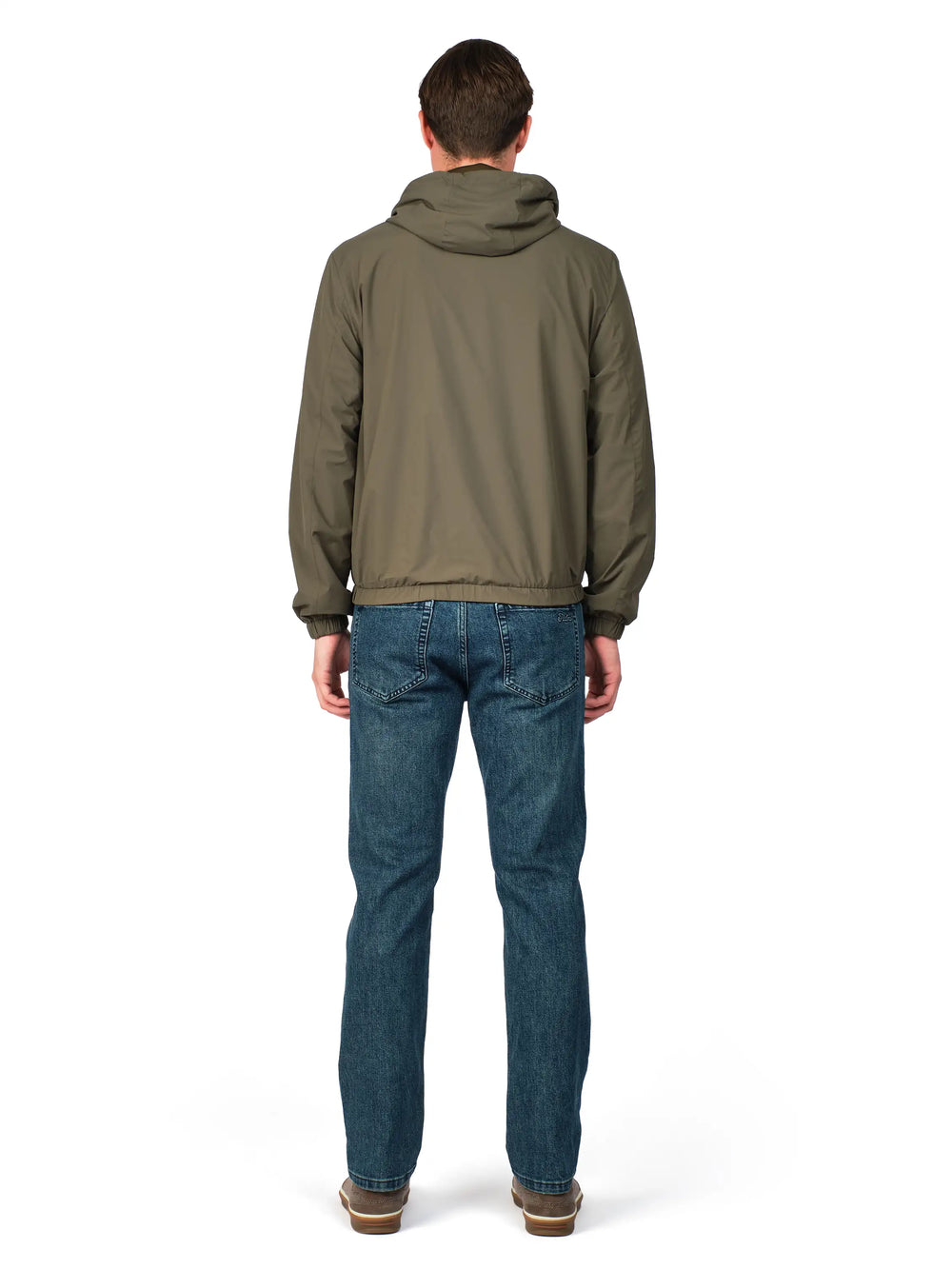 Person wearing a green jacket and blue jeans on a white background