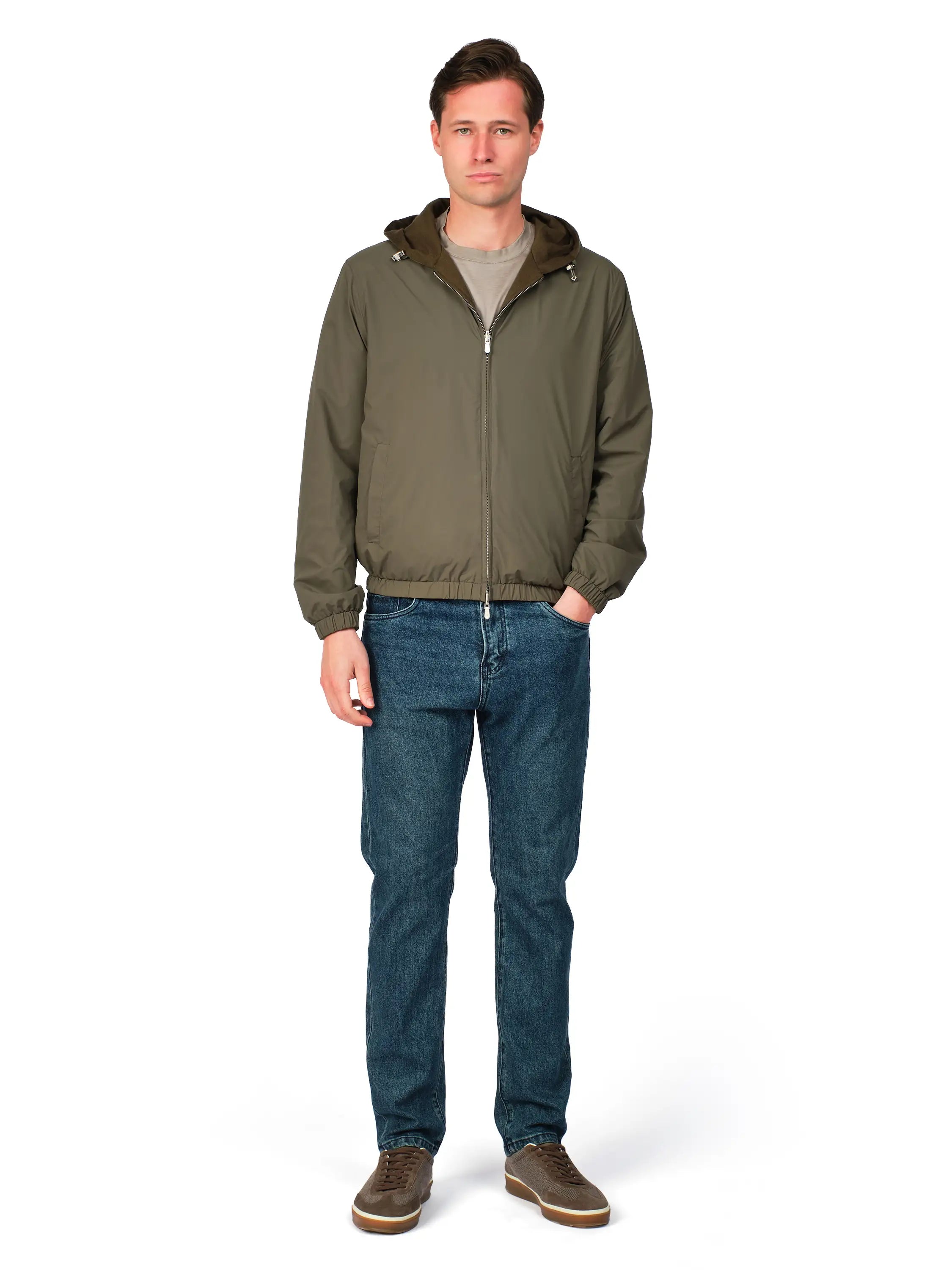 Man wearing a green jacket and blue jeans on a white background