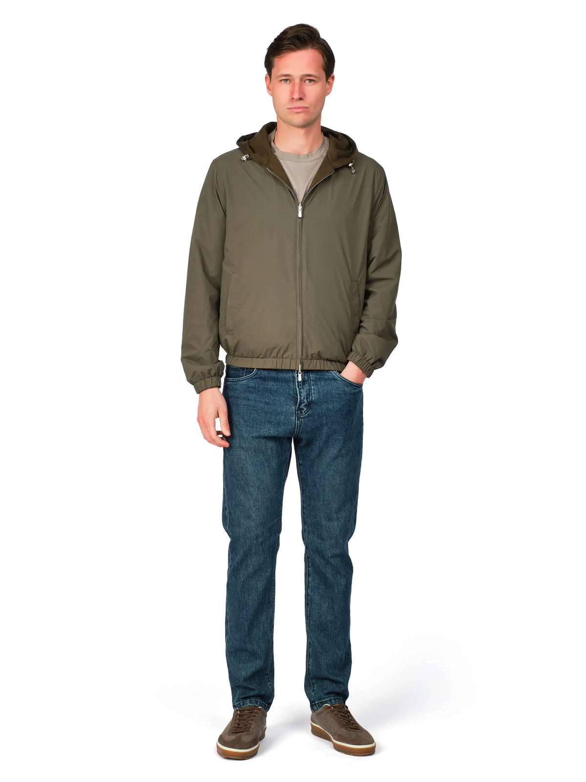 Man wearing a green jacket and blue jeans on a white background