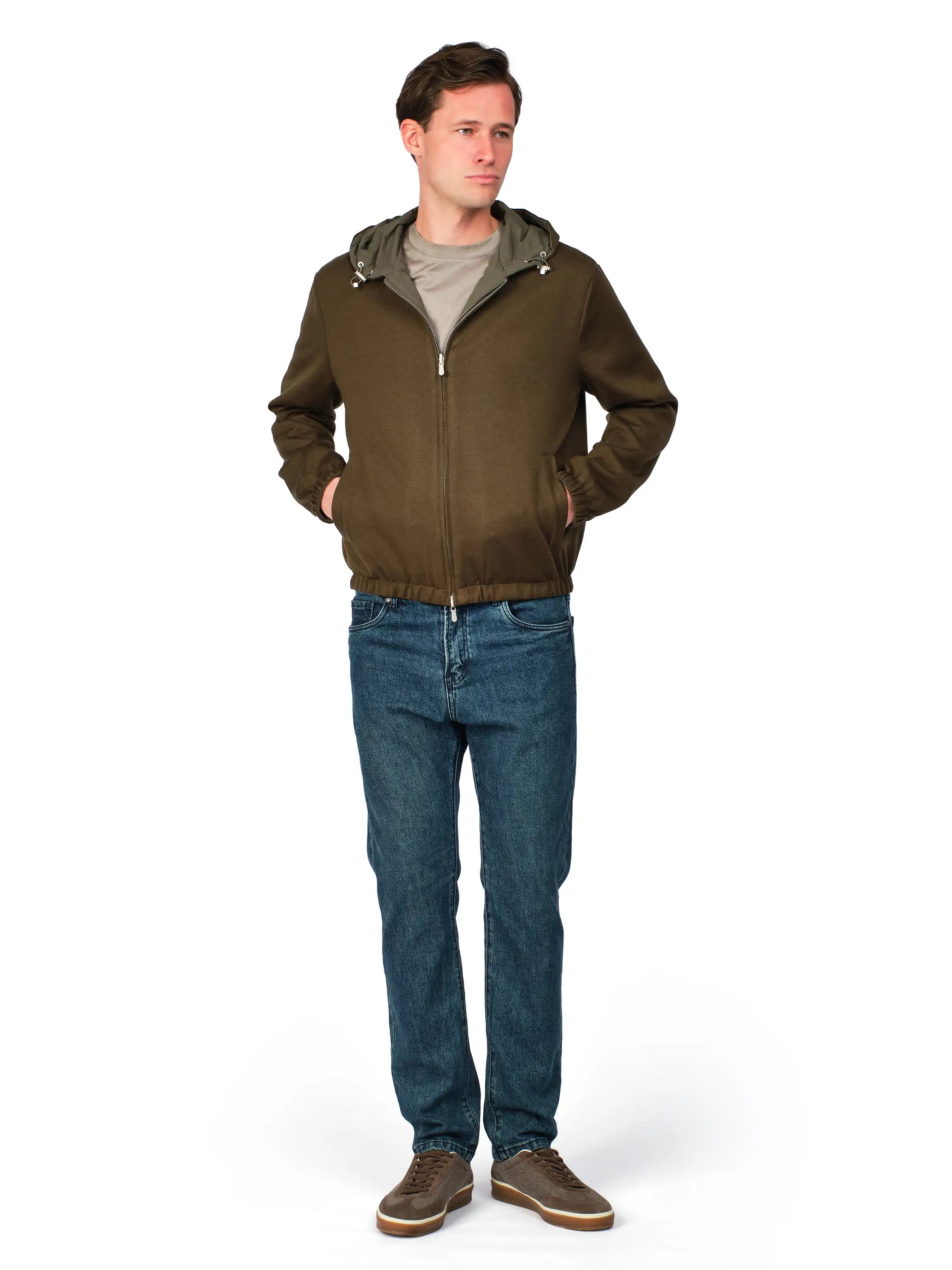 Man wearing a brown jacket with a hood, gray shirt, blue jeans, and brown shoes on a white background