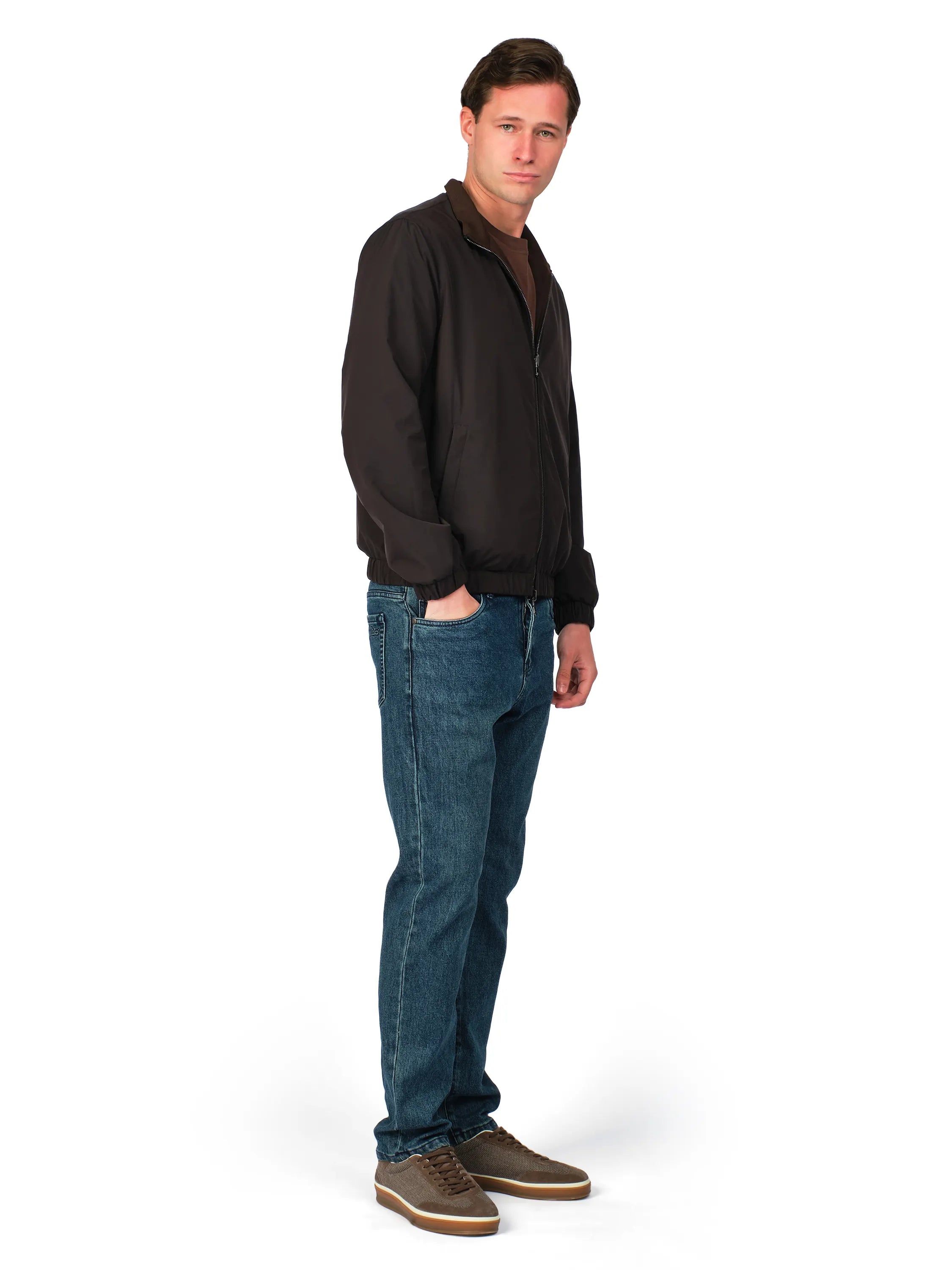Man wearing a black jacket and blue jeans on a white background