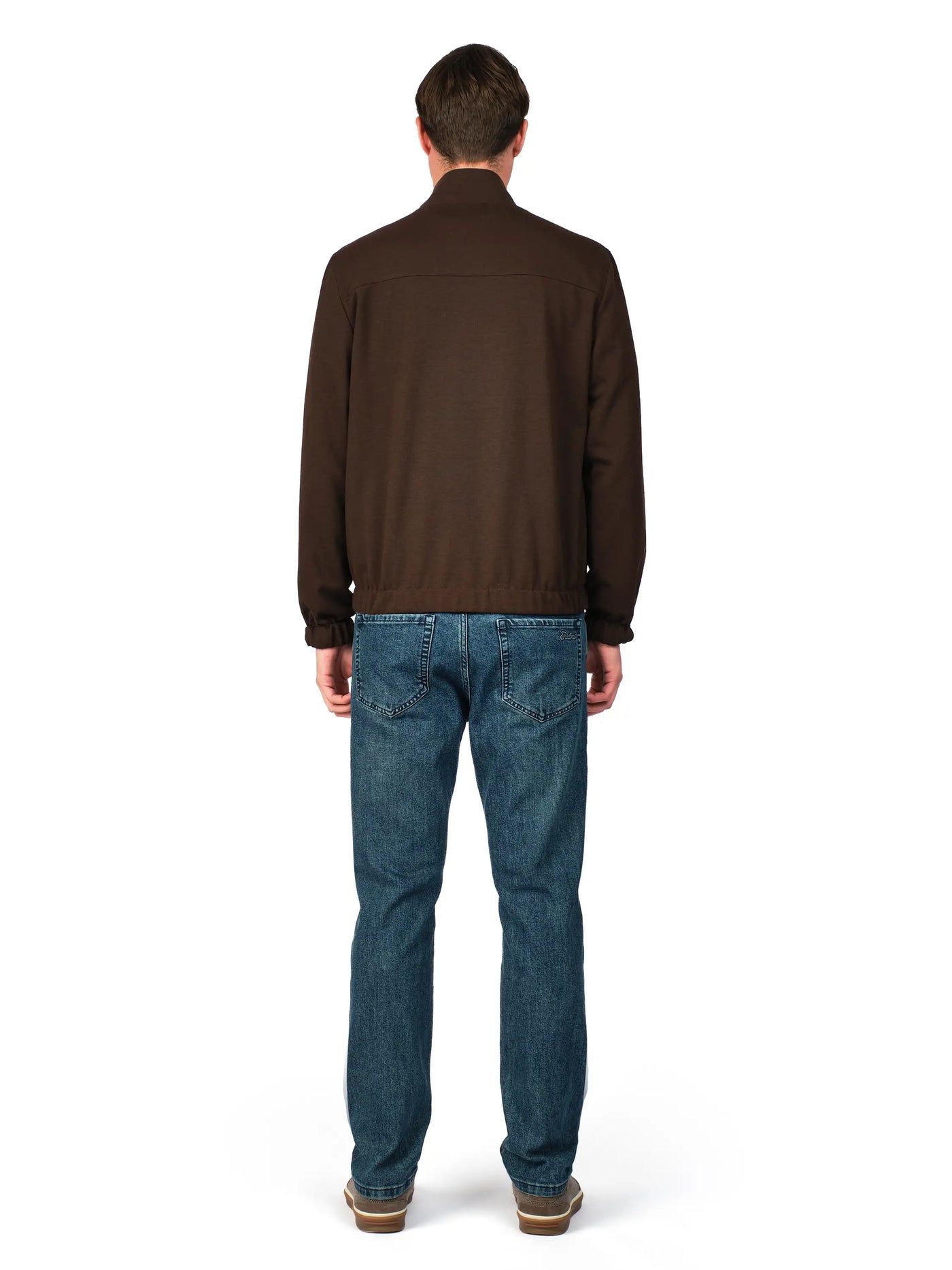 Man wearing a brown jacket and blue jeans on a white background