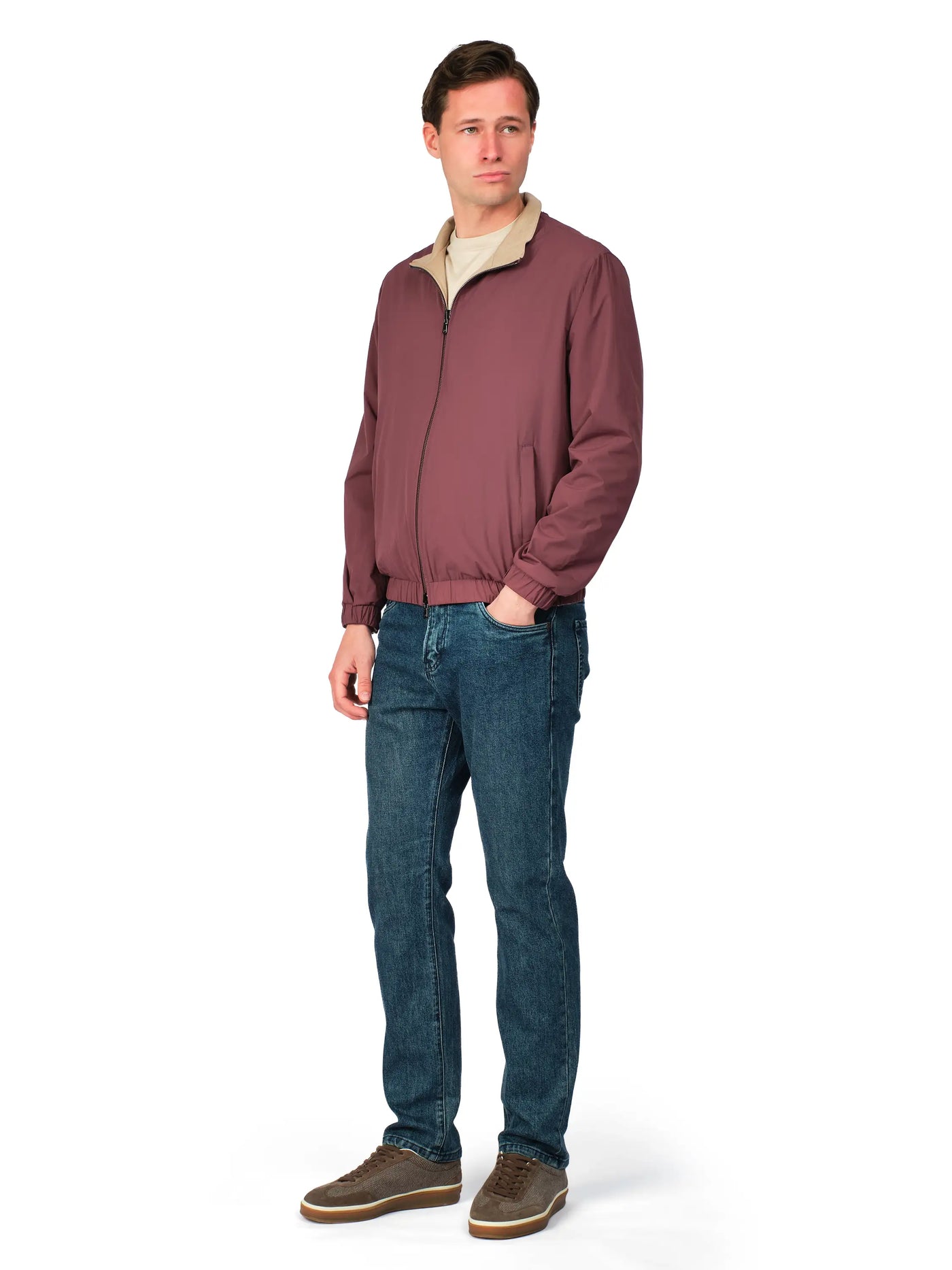 Man wearing a maroon jacket and blue jeans on a white background