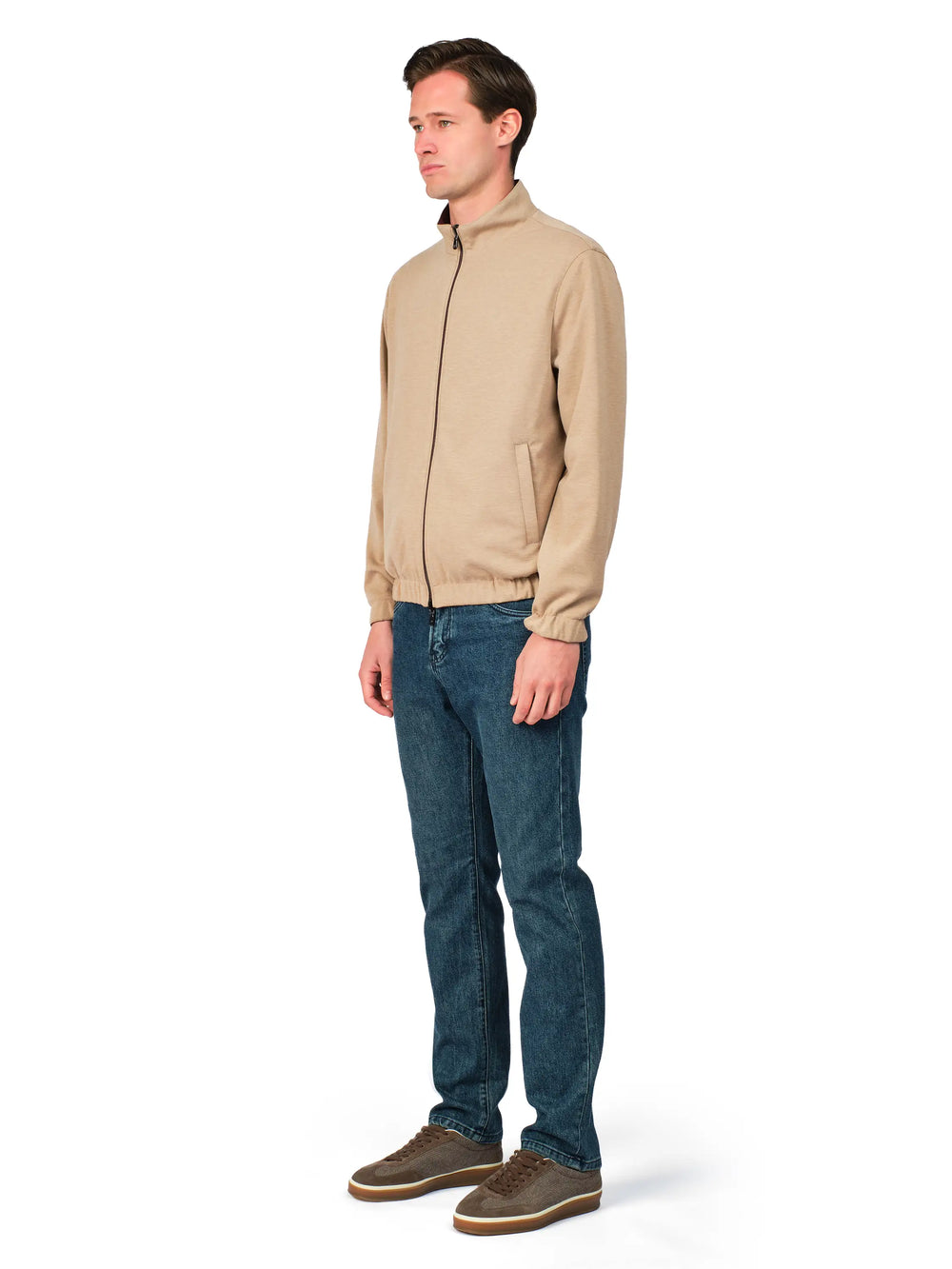 Man wearing a beige jacket and blue jeans on a white background