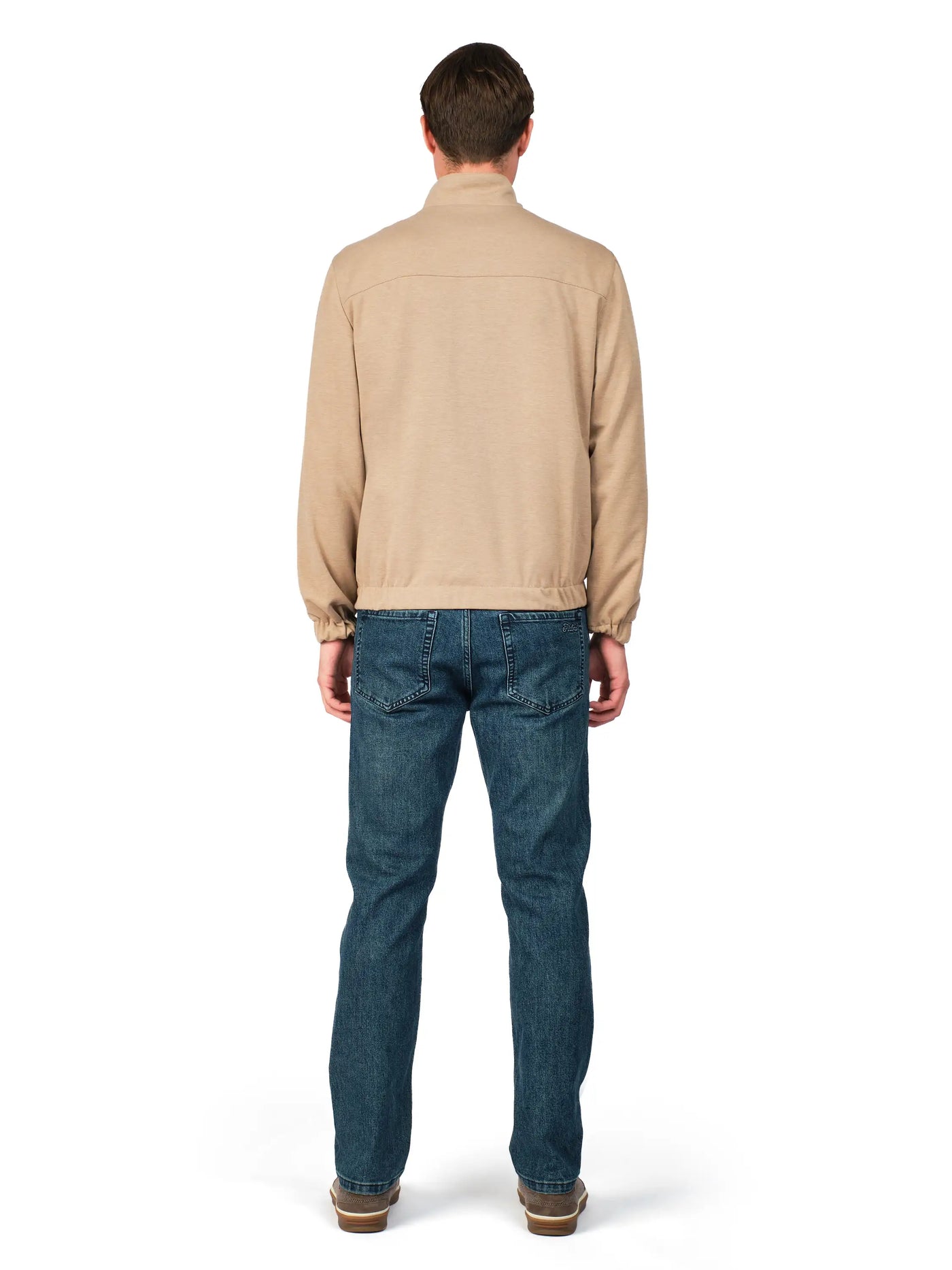 Man wearing a beige jacket and blue jeans on a white background