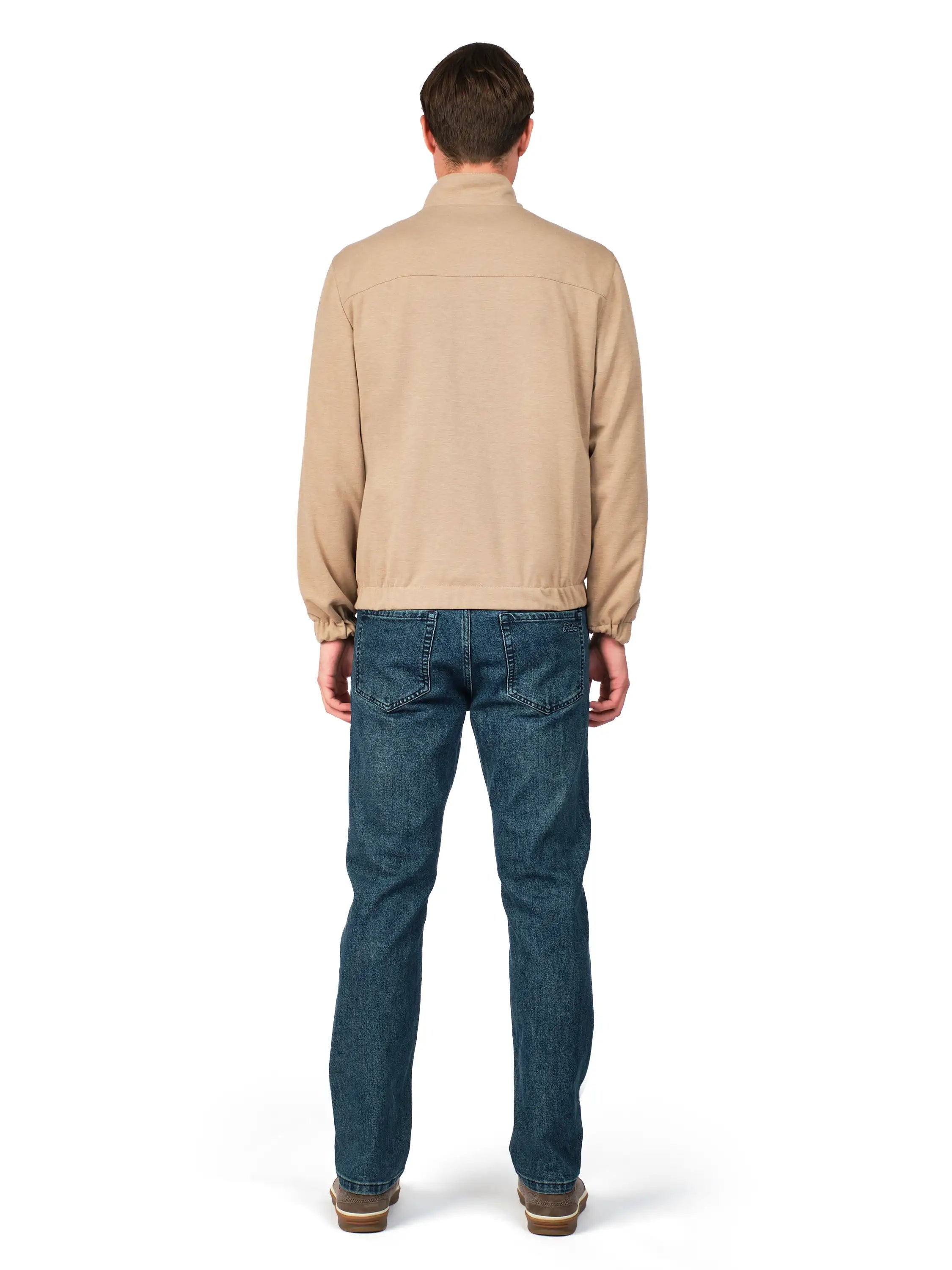 Man wearing a beige jacket and blue jeans on a white background