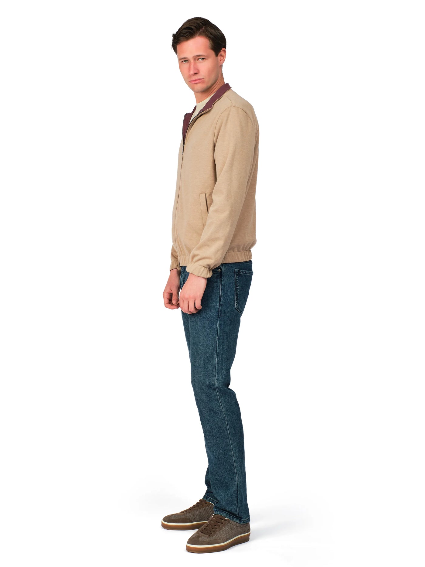 Man wearing a beige jacket and blue jeans on a white background
