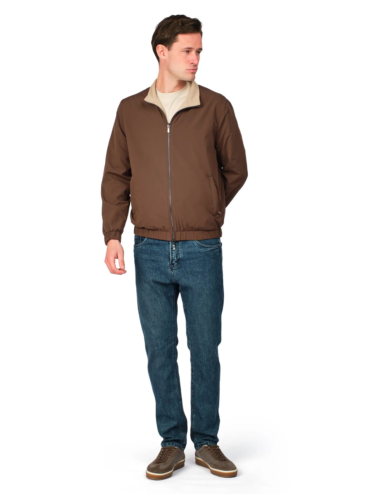 Man wearing a brown jacket and blue jeans on a white background