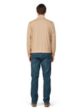 Man wearing a beige sweater and blue jeans on a white background