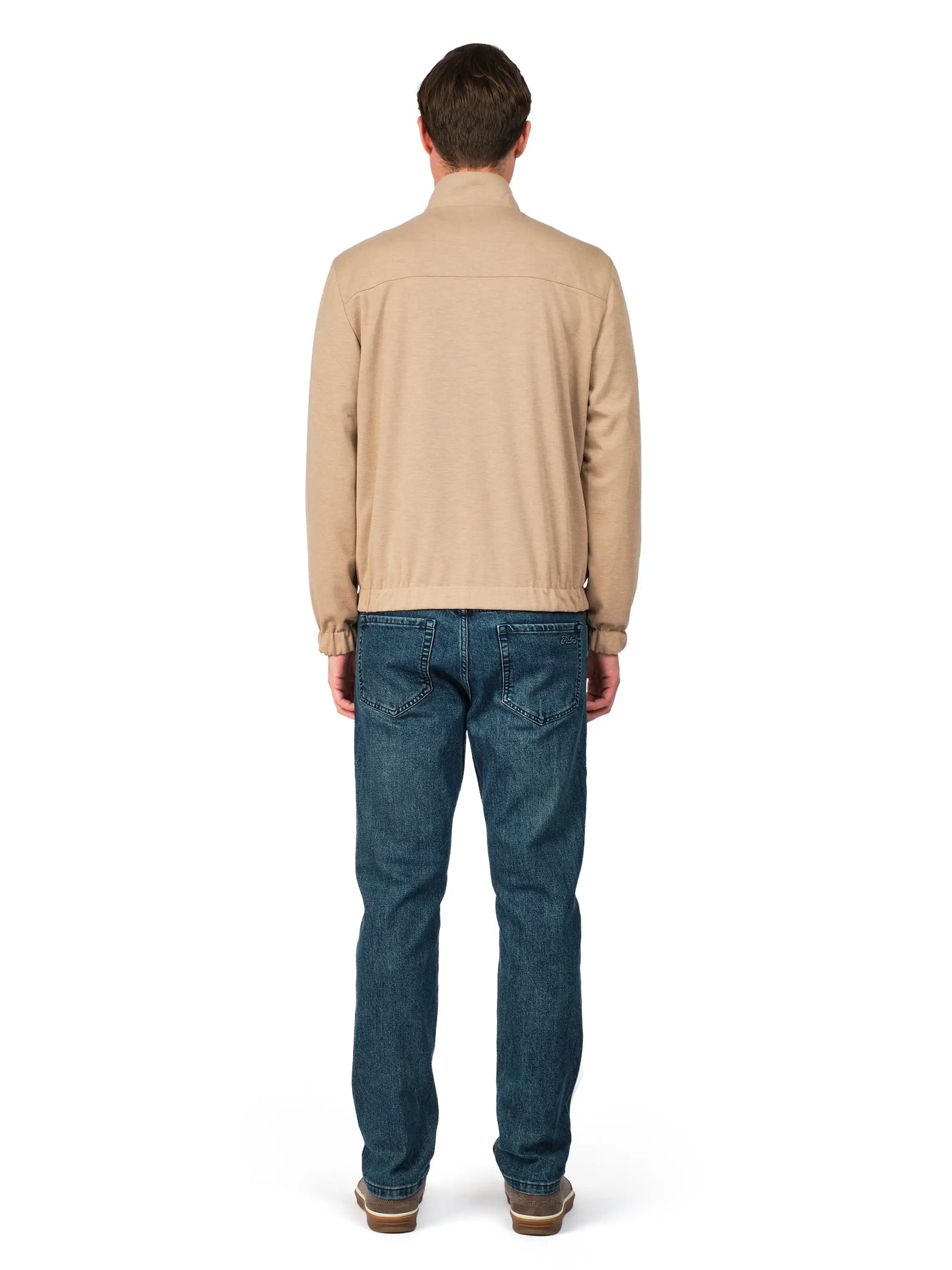 Man wearing a beige sweater and blue jeans on a white background