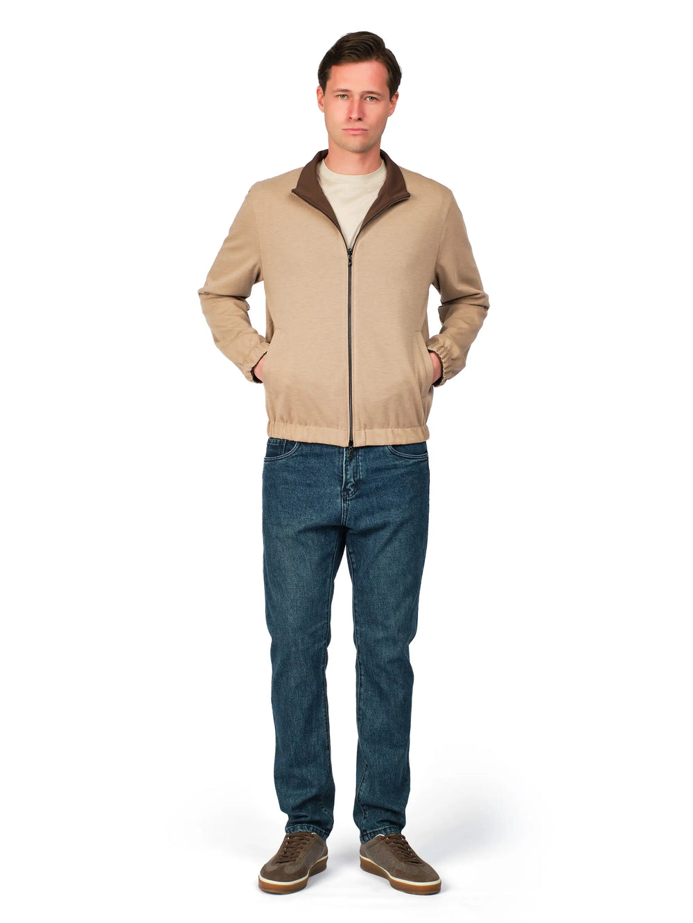 Man wearing a beige jacket and blue jeans on a white background