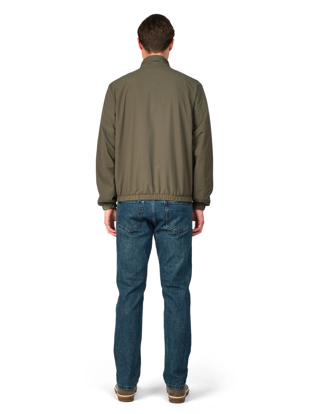 Man wearing a green jacket and blue jeans on a white background