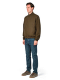 Man wearing a green jacket and blue jeans on a white background