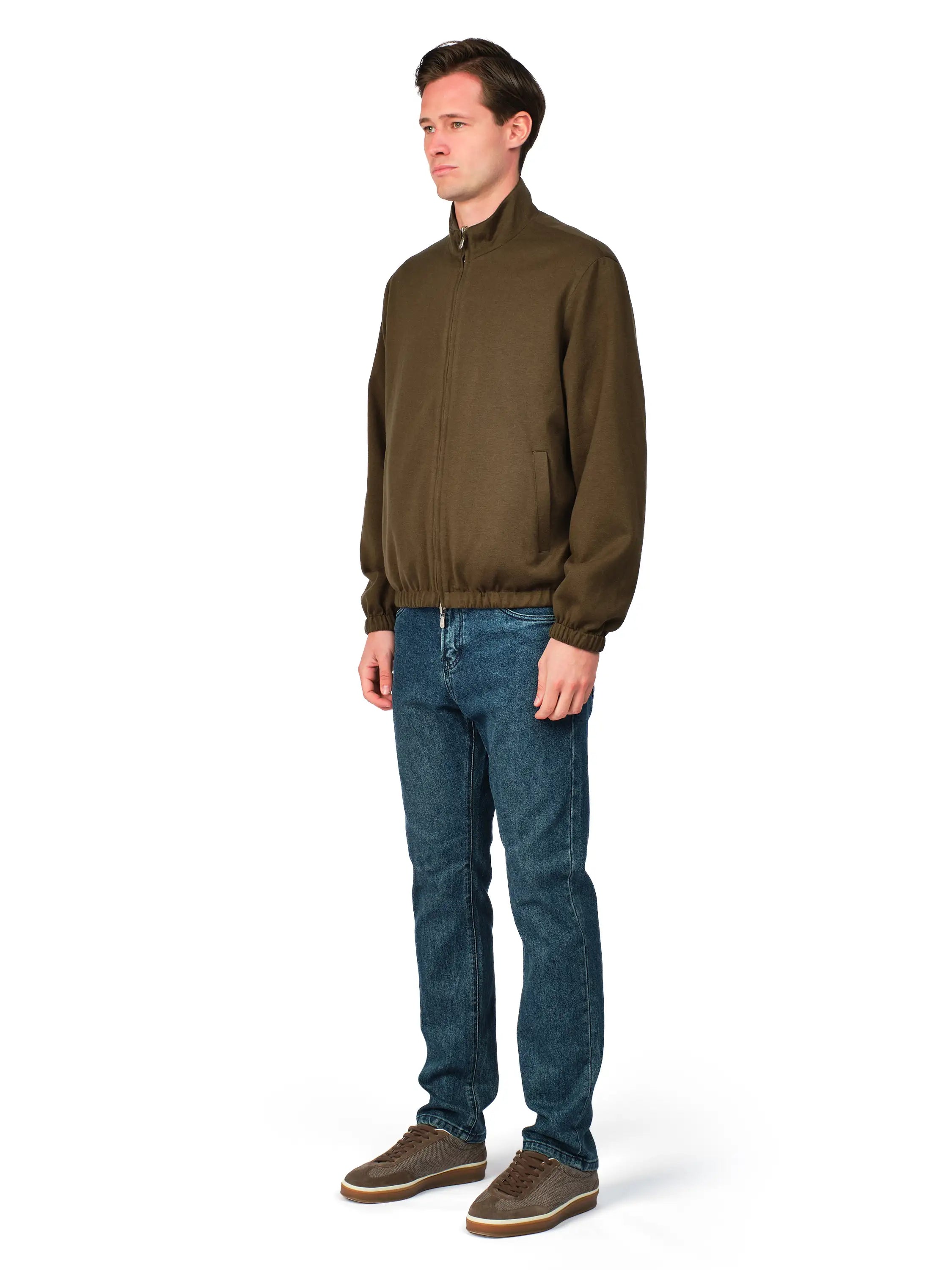 Man wearing a green jacket and blue jeans on a white background