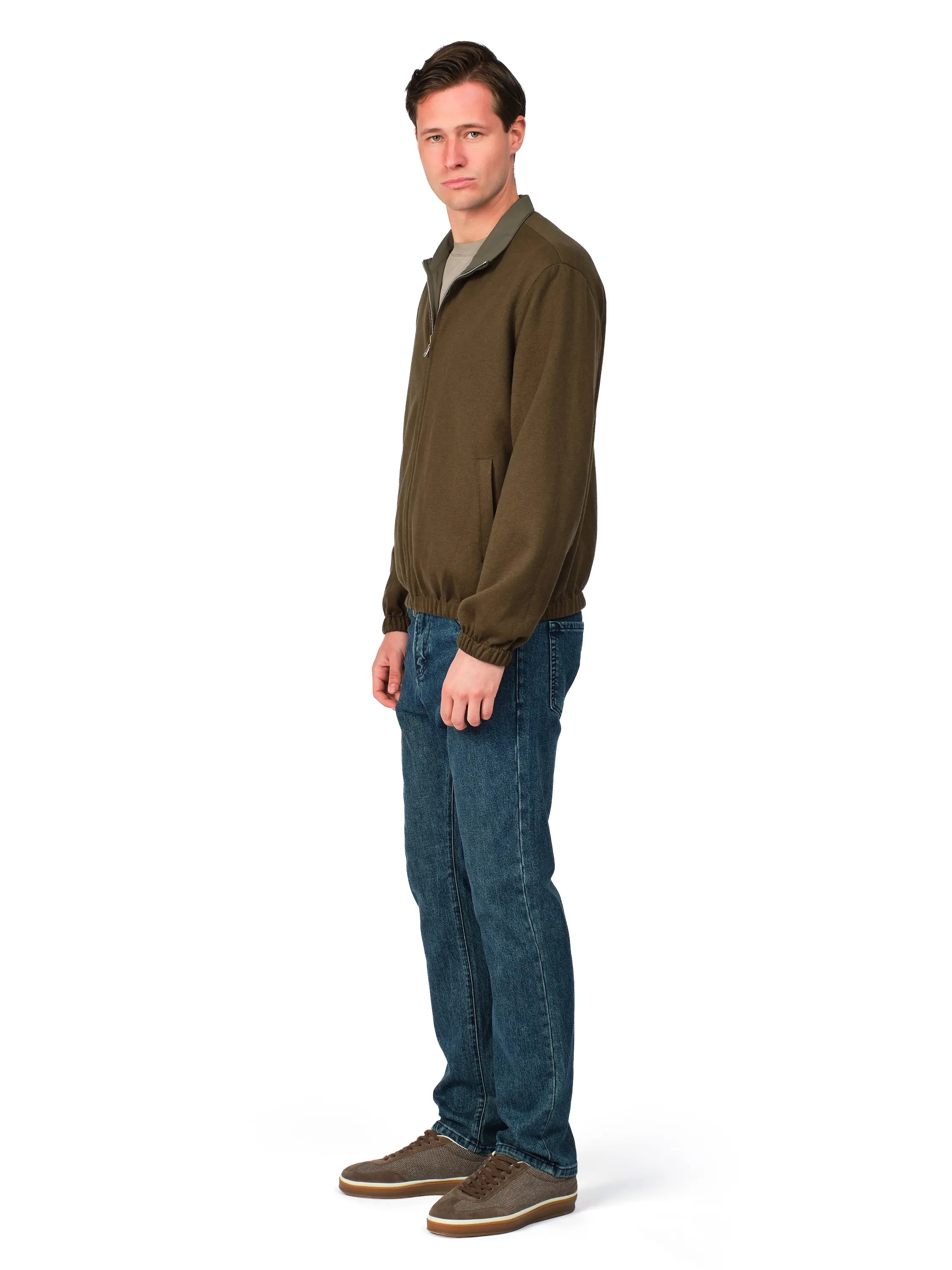Man wearing a green jacket and blue jeans on a white background