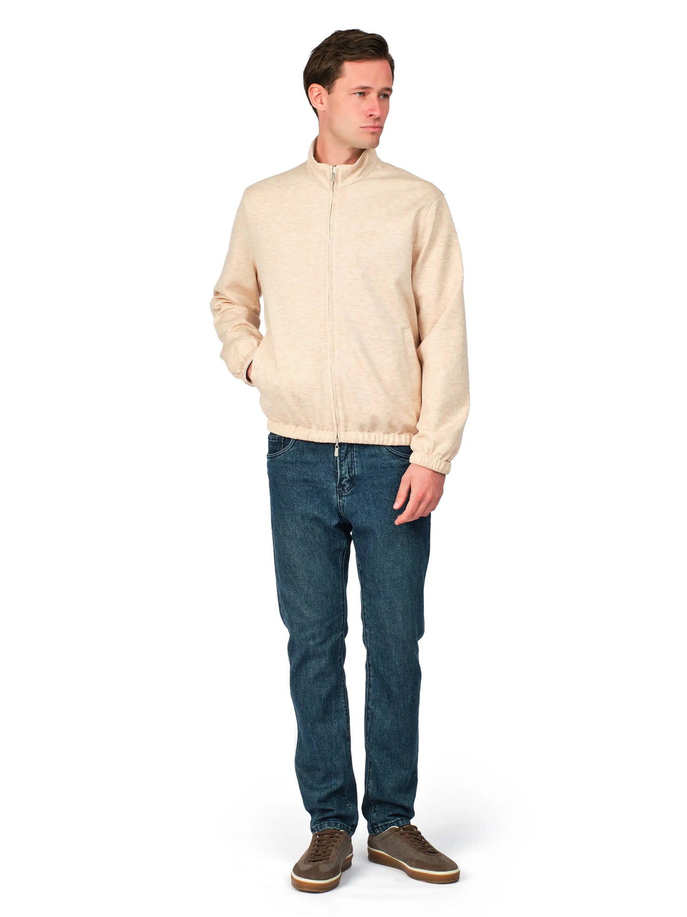 Man wearing a beige jacket and blue jeans on a white background