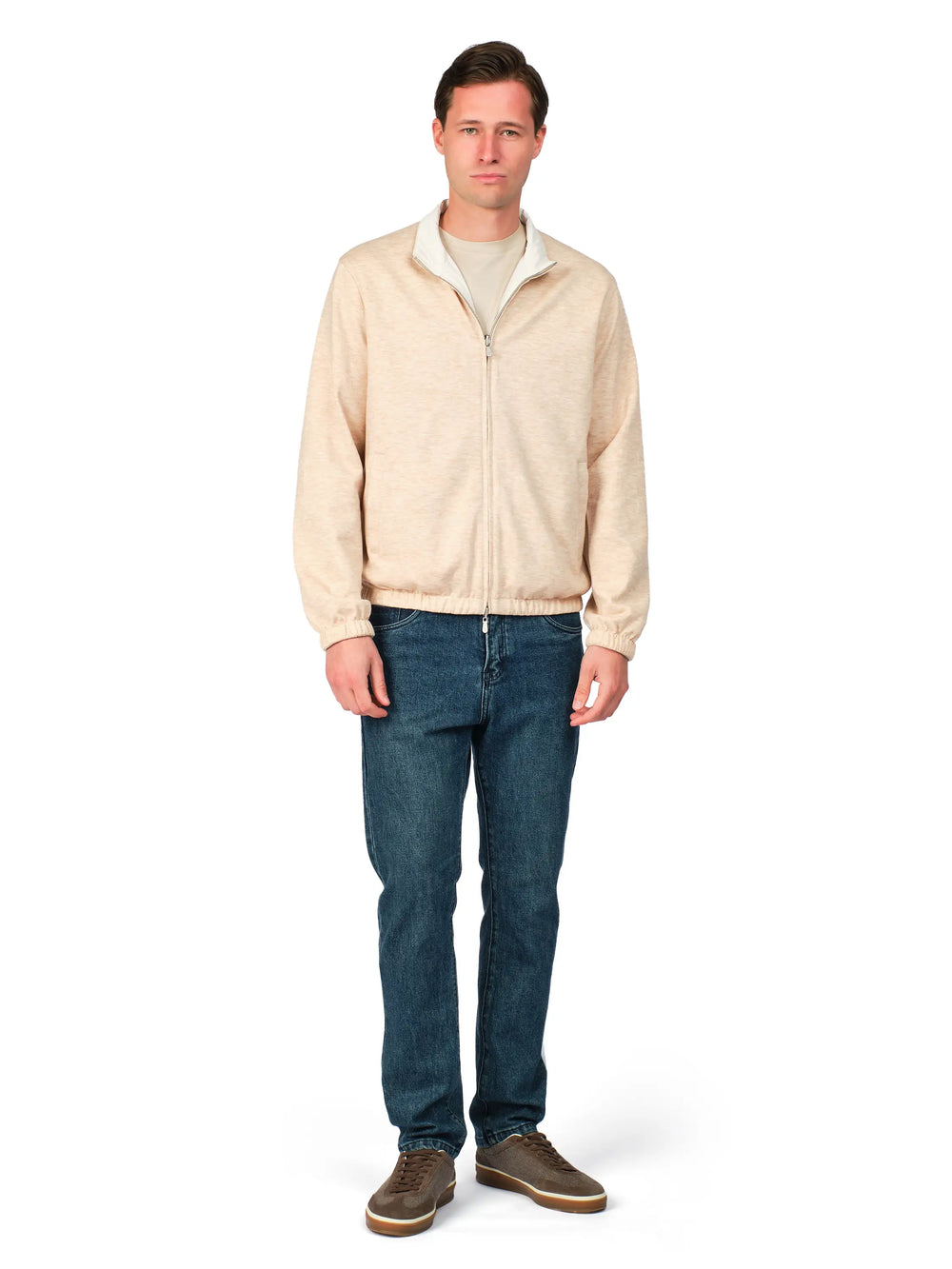 Man wearing a beige jacket and blue jeans on a white background