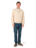 Man wearing a beige jacket and blue jeans on a white background
