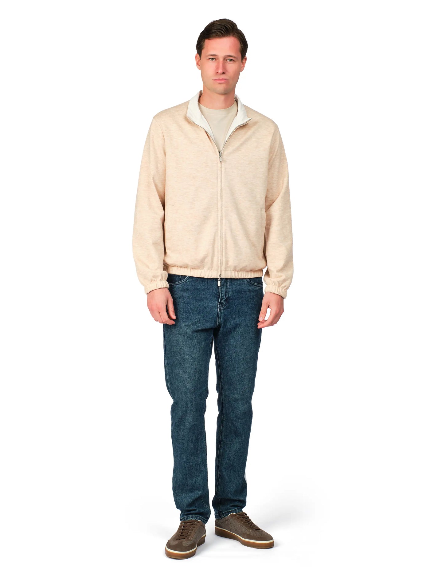 Man wearing a beige jacket and blue jeans on a white background