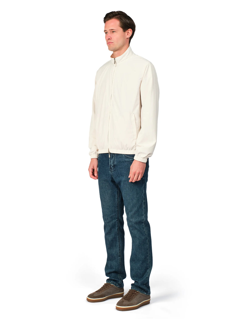 Man wearing a cream shirt and blue jeans on a white background