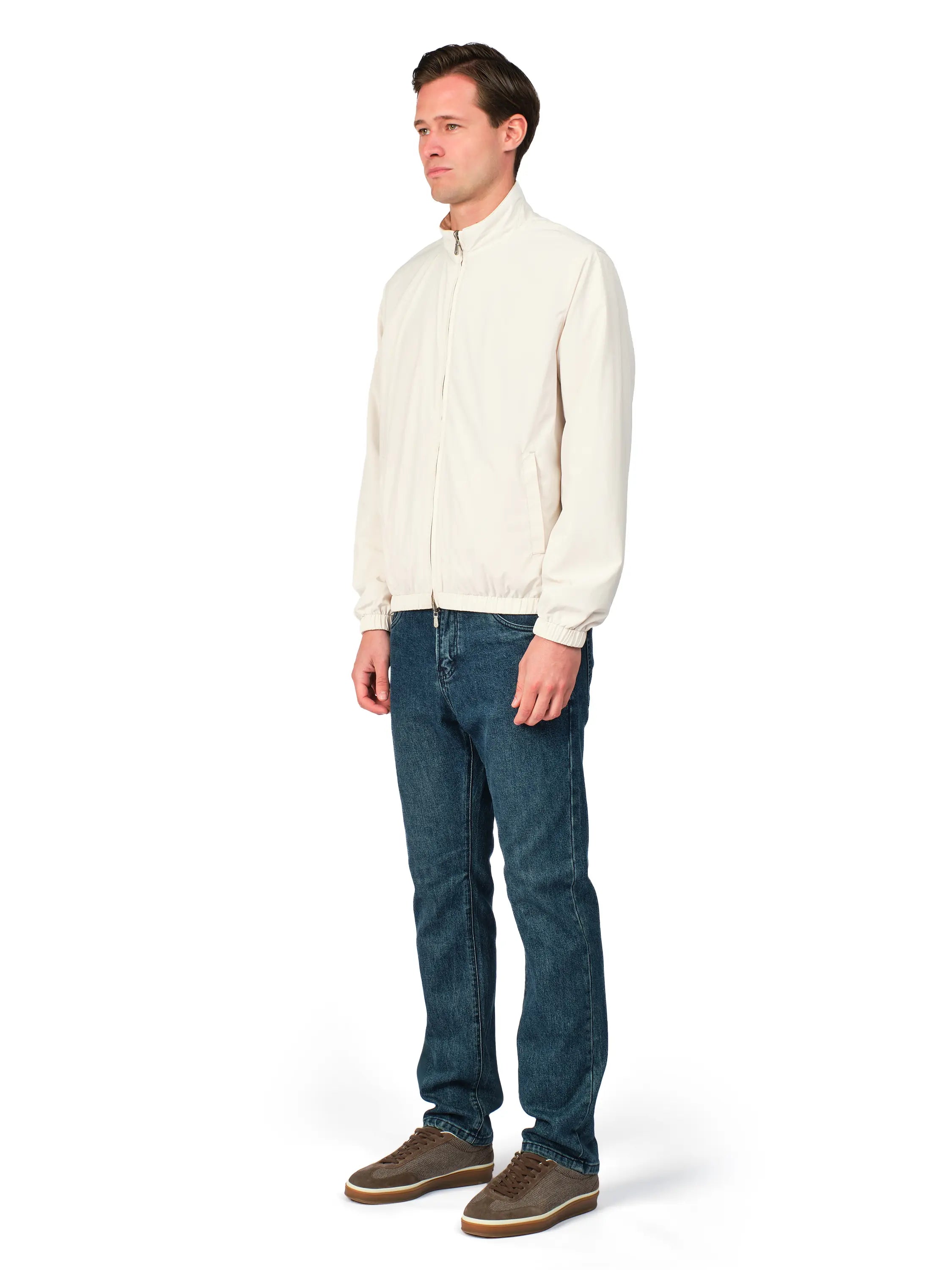Man wearing a cream shirt and blue jeans on a white background