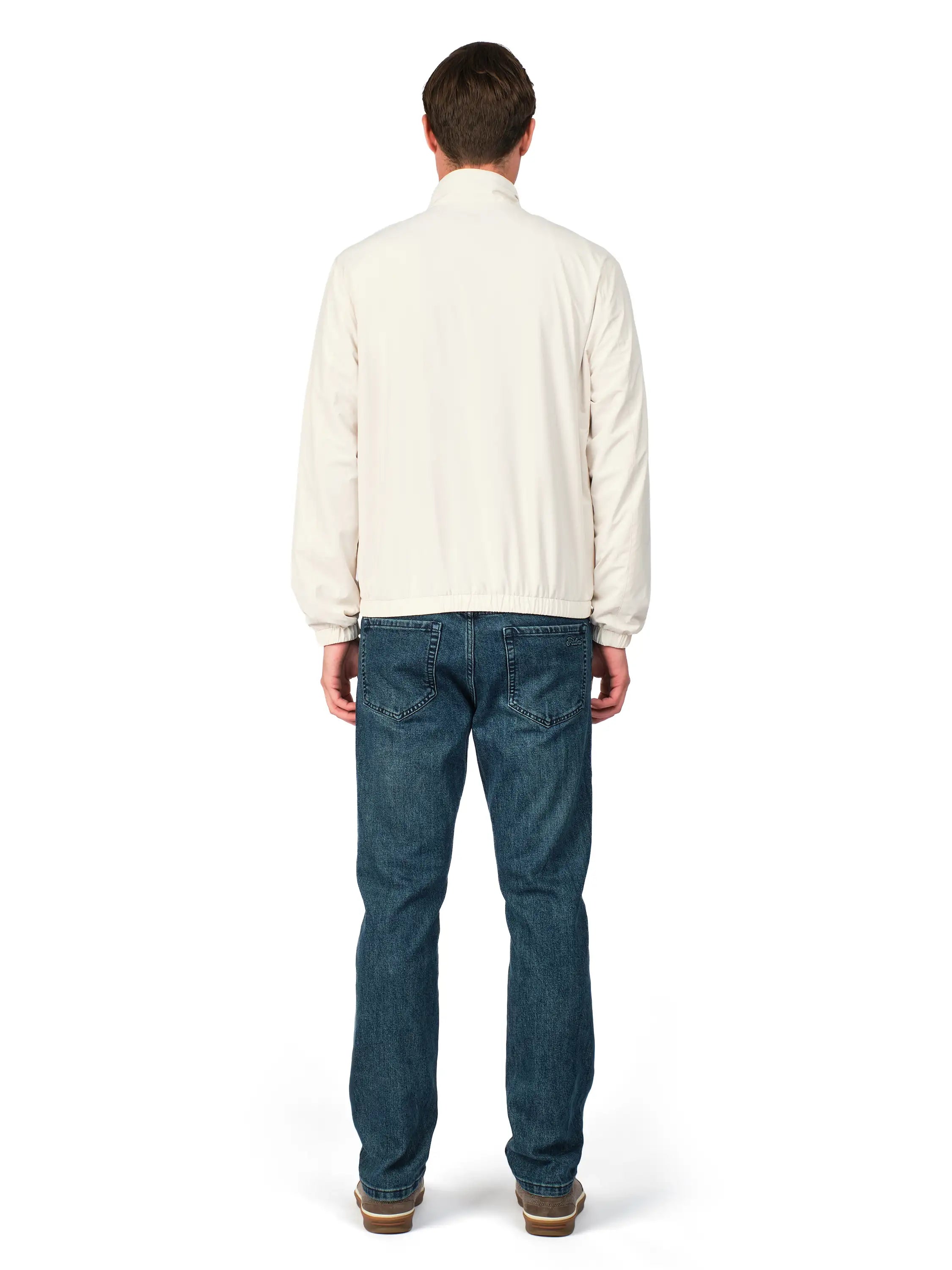 Man wearing a cream shirt and blue jeans on a white background