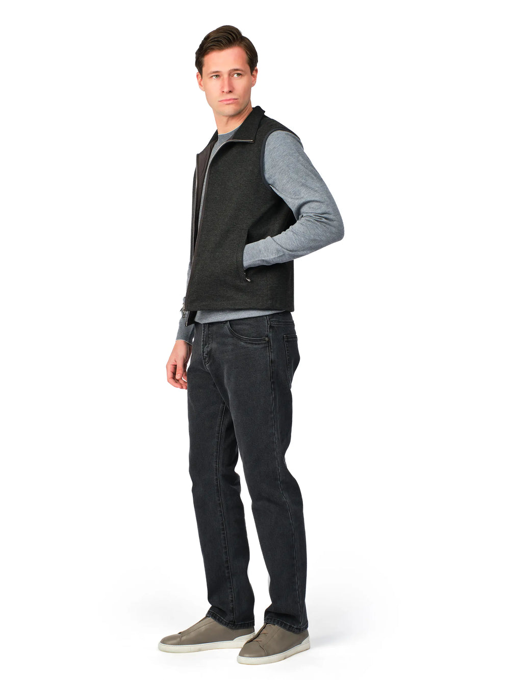 Man wearing a gray sweater with a black vest over it on a white background