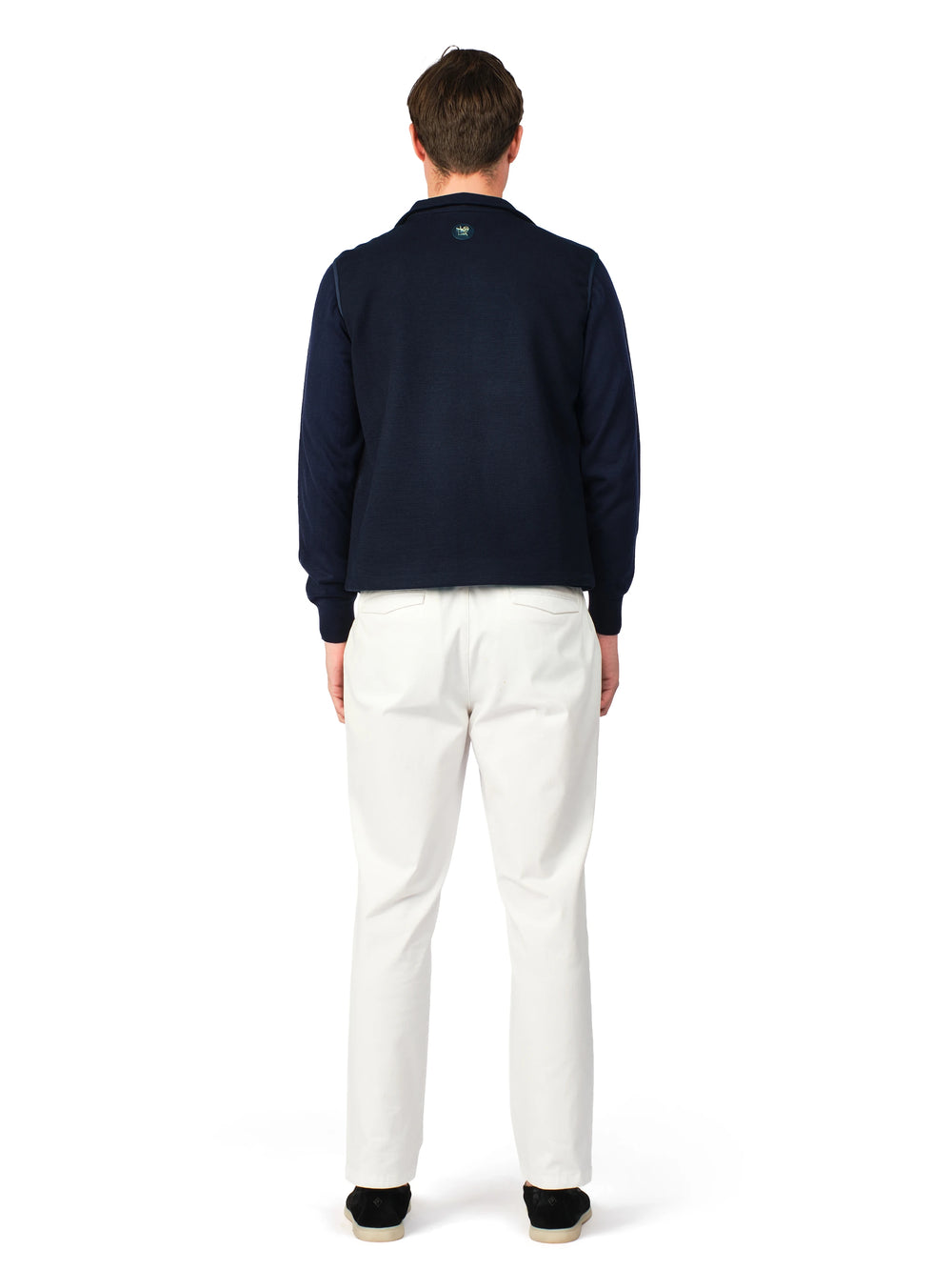 Person wearing a navy sweater and white pants on a white background