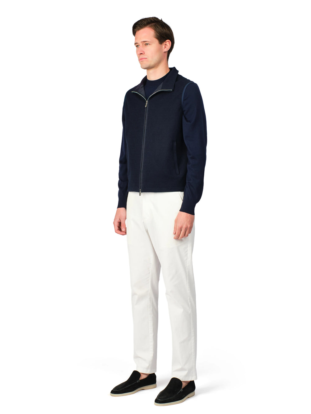 Man wearing a navy jacket and white pants on a white background