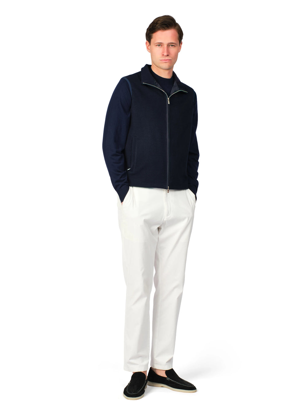 Man wearing a navy jacket and white pants on a white background