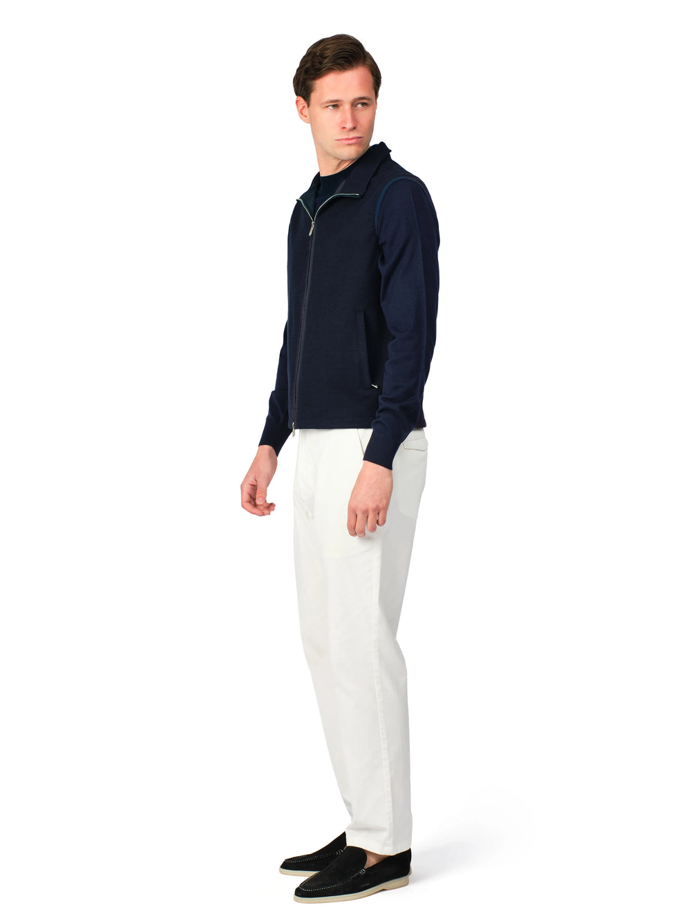 Man wearing a navy half-zip sweater and white pants on a white background
