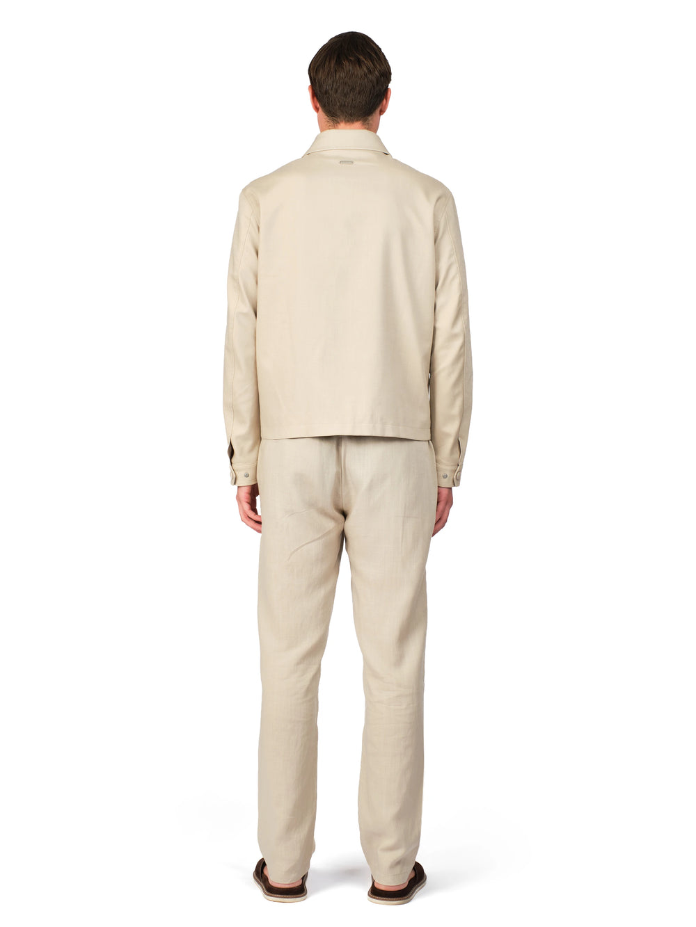 Man wearing a beige suit standing against a white background