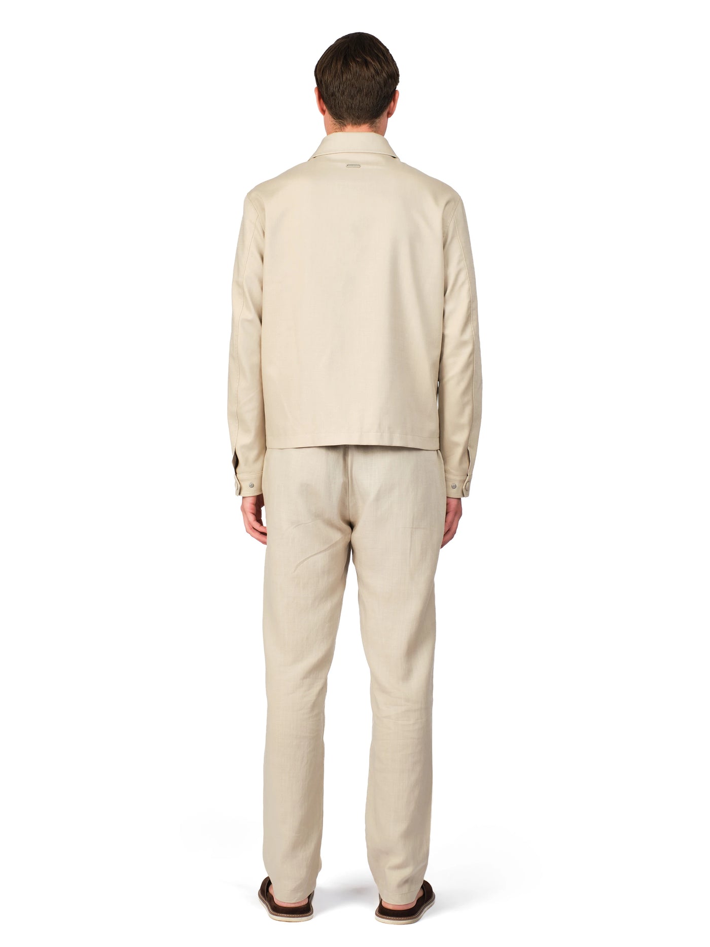 Man wearing a beige suit standing against a white background