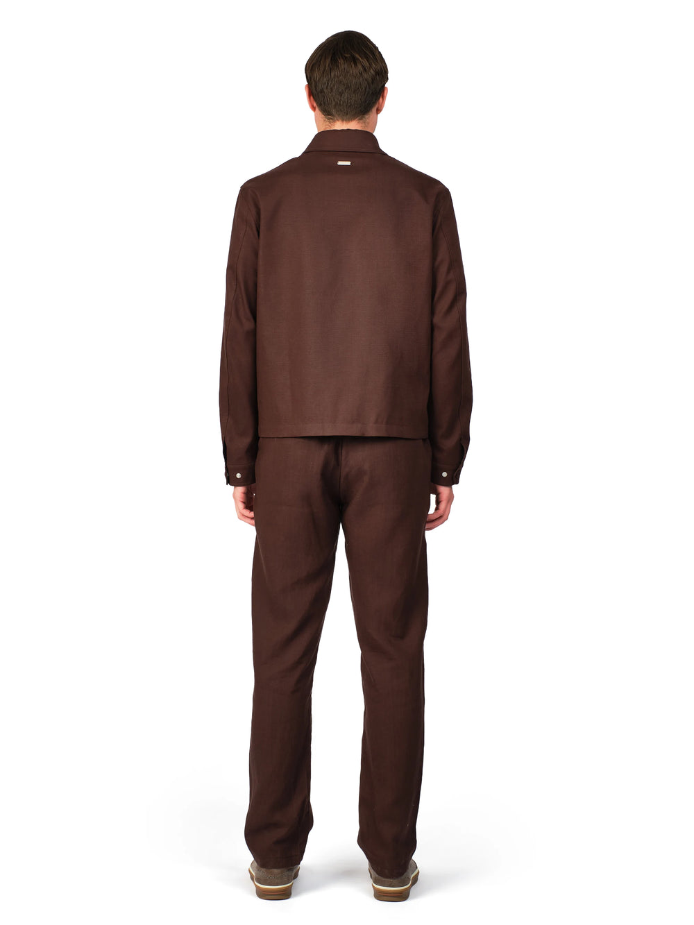 Man wearing a brown suit standing against a white background
