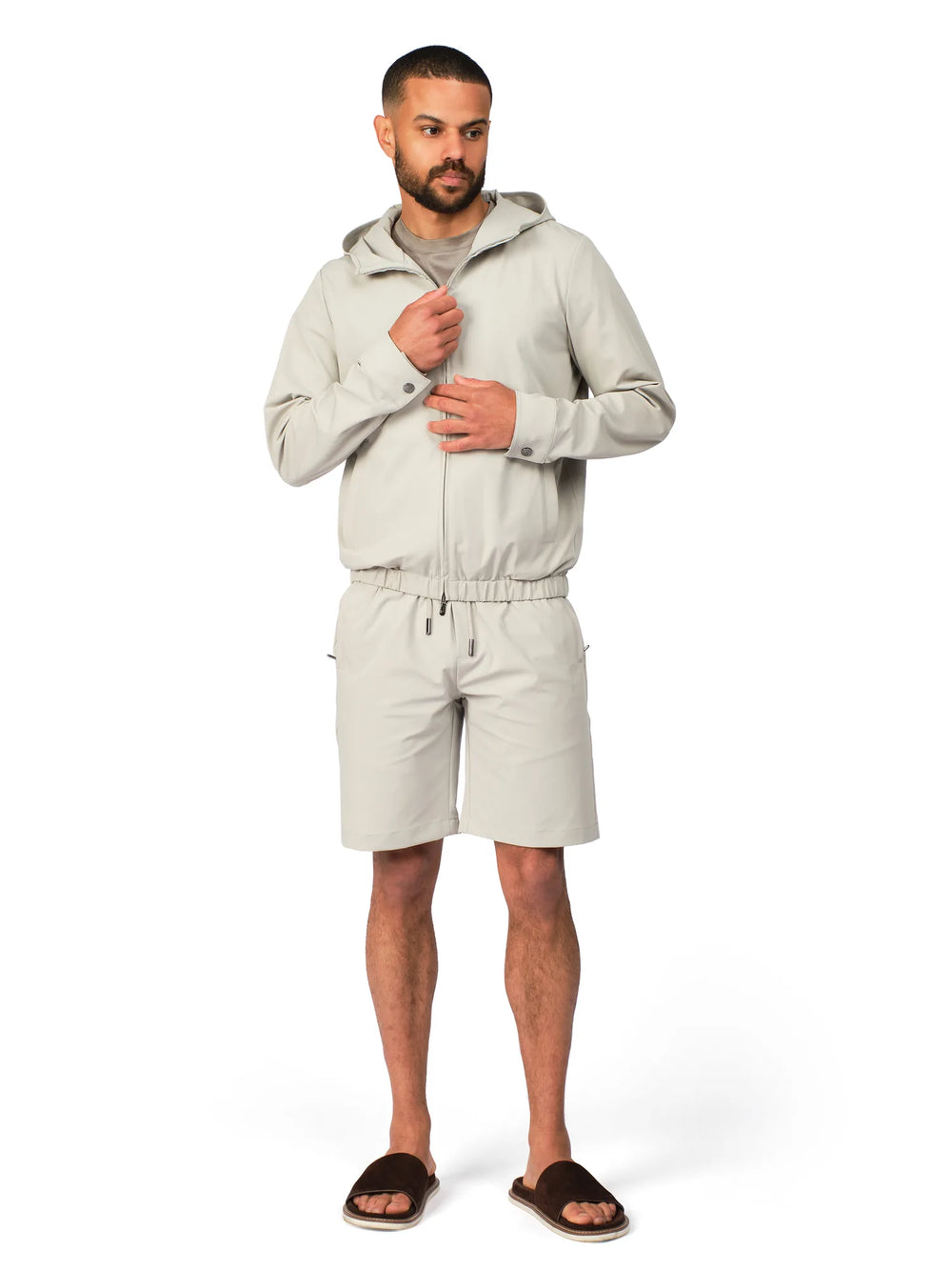Man wearing a light gray hoodie and shorts on a white background