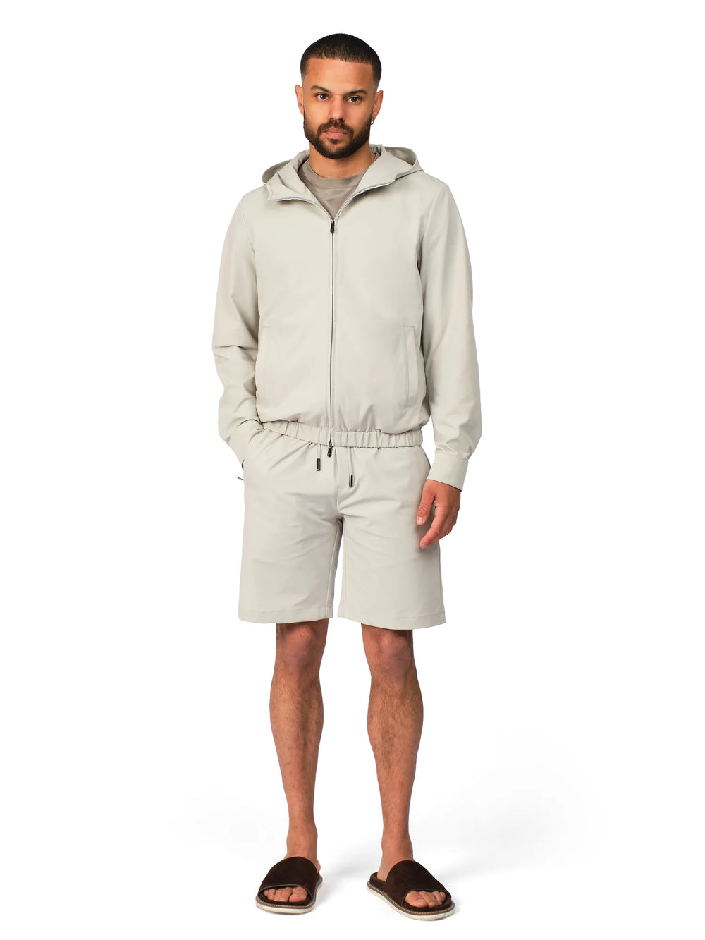 Man wearing a beige tracksuit on a white background