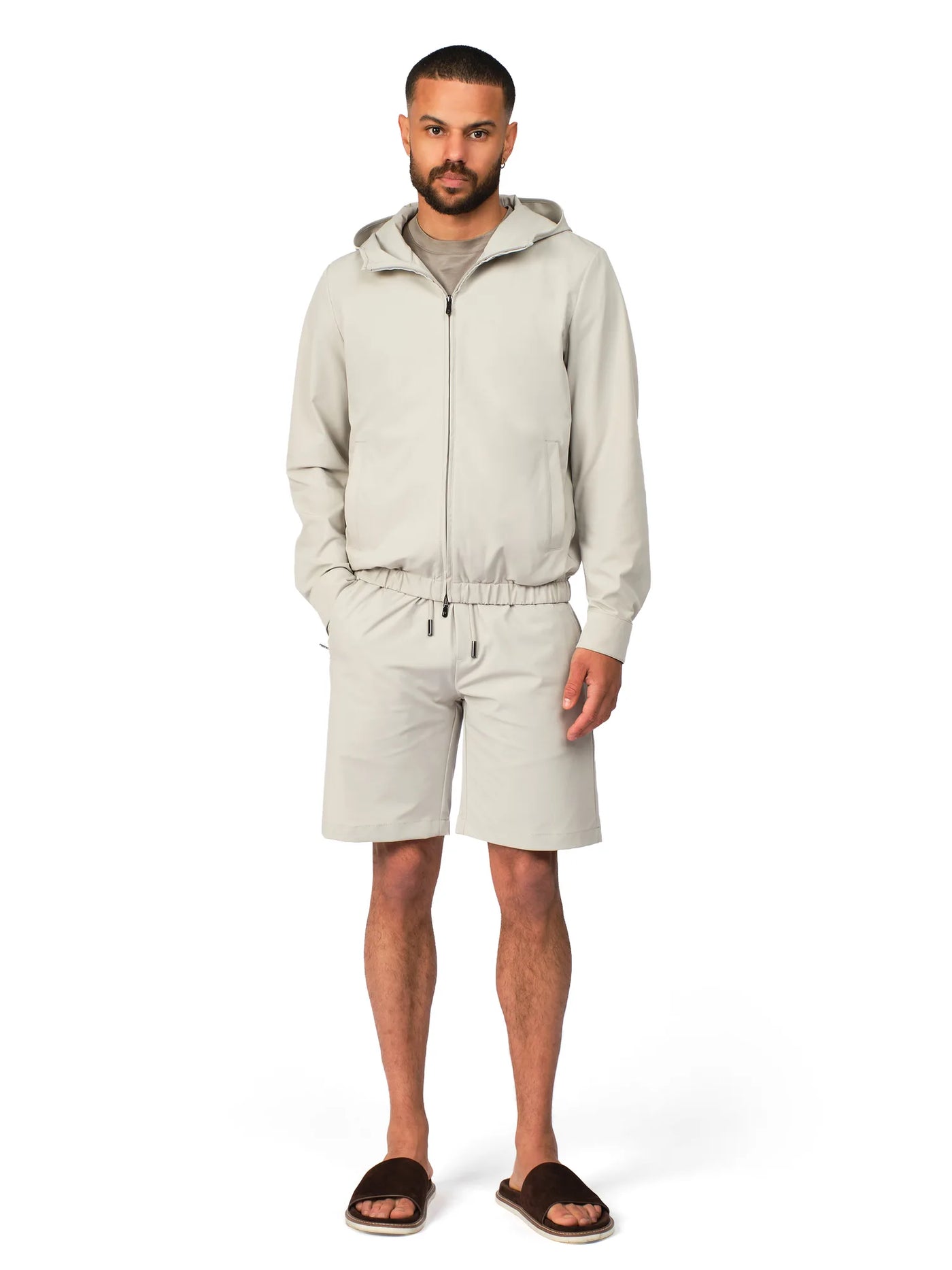 Man wearing a beige tracksuit on a white background