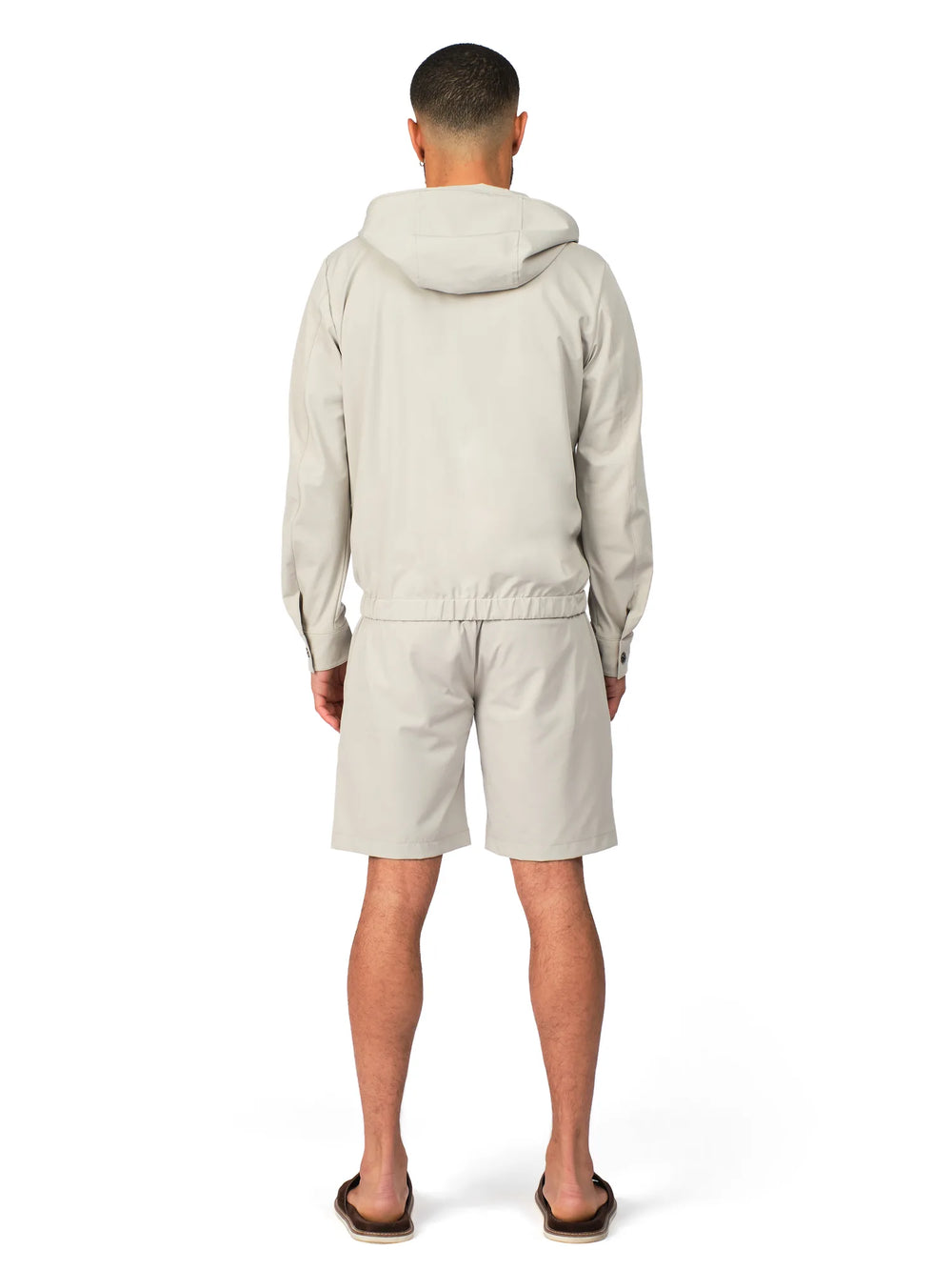 Person wearing a light gray hoodie and shorts set on a white background