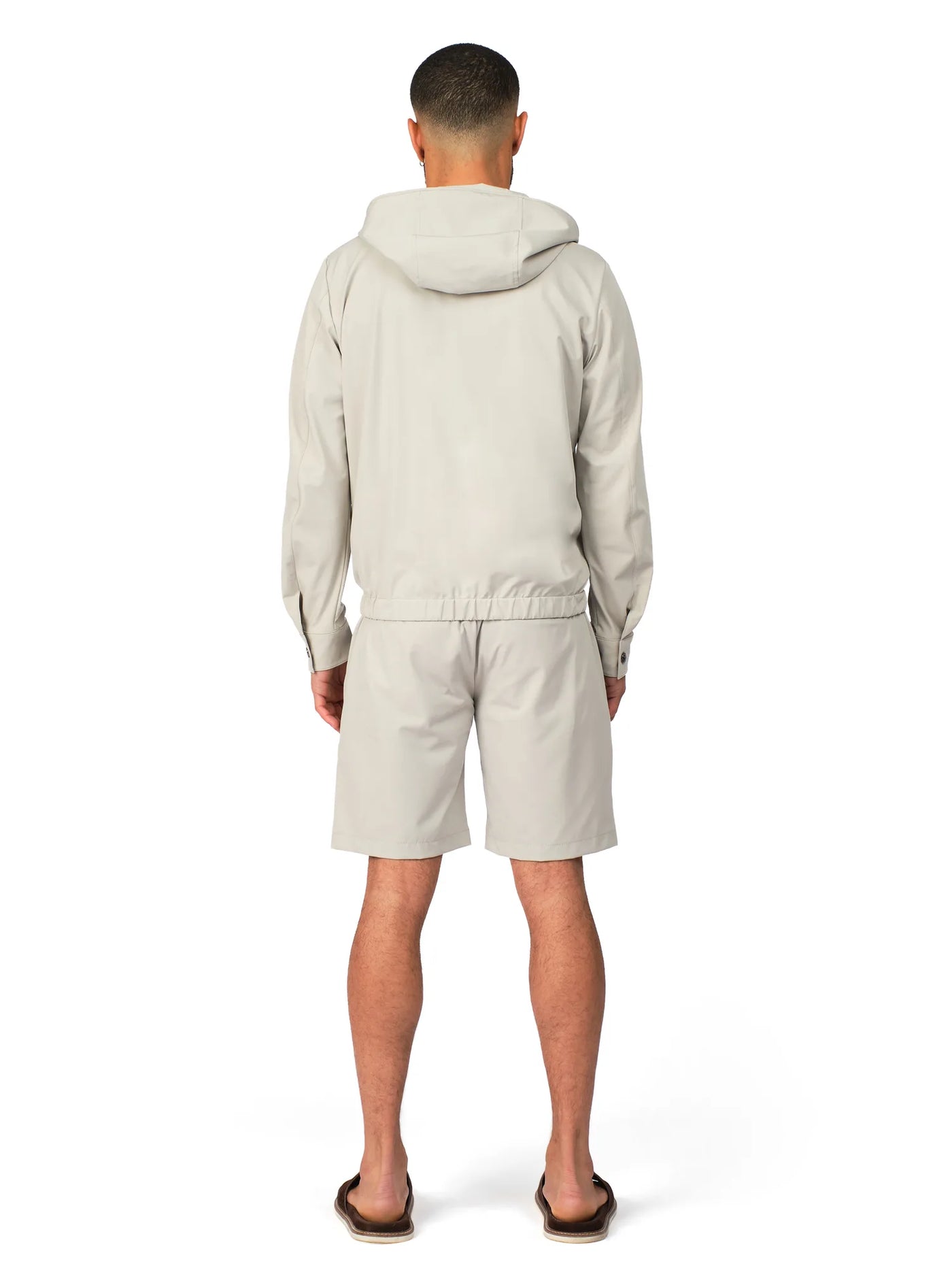 Person wearing a light gray hoodie and shorts set on a white background