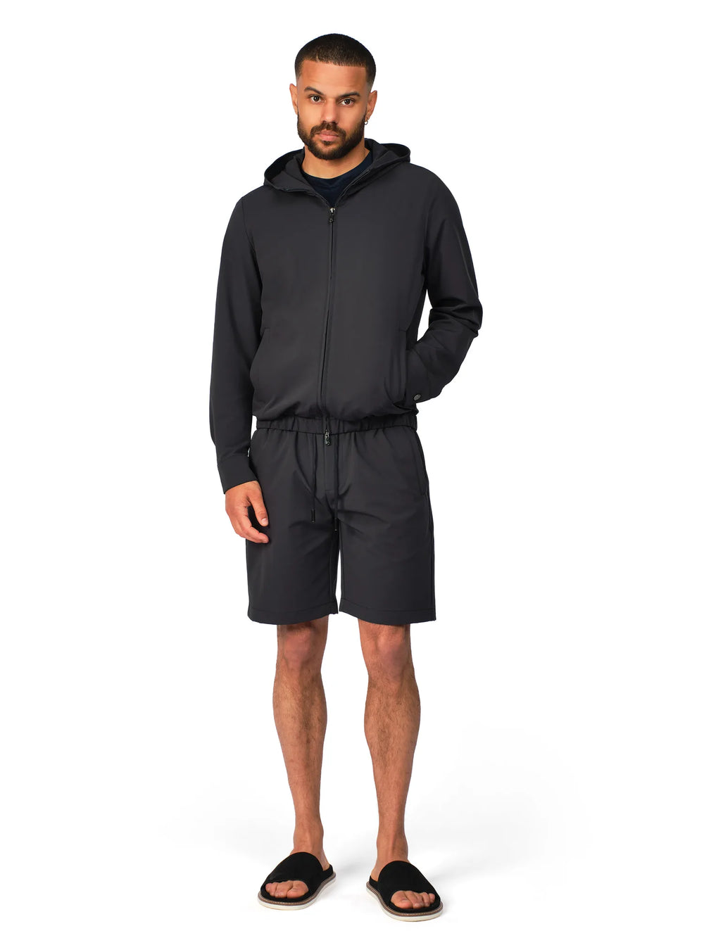 Man wearing a black hoodie and shorts set on a white background