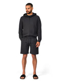 Man wearing a black hoodie and shorts set on a white background