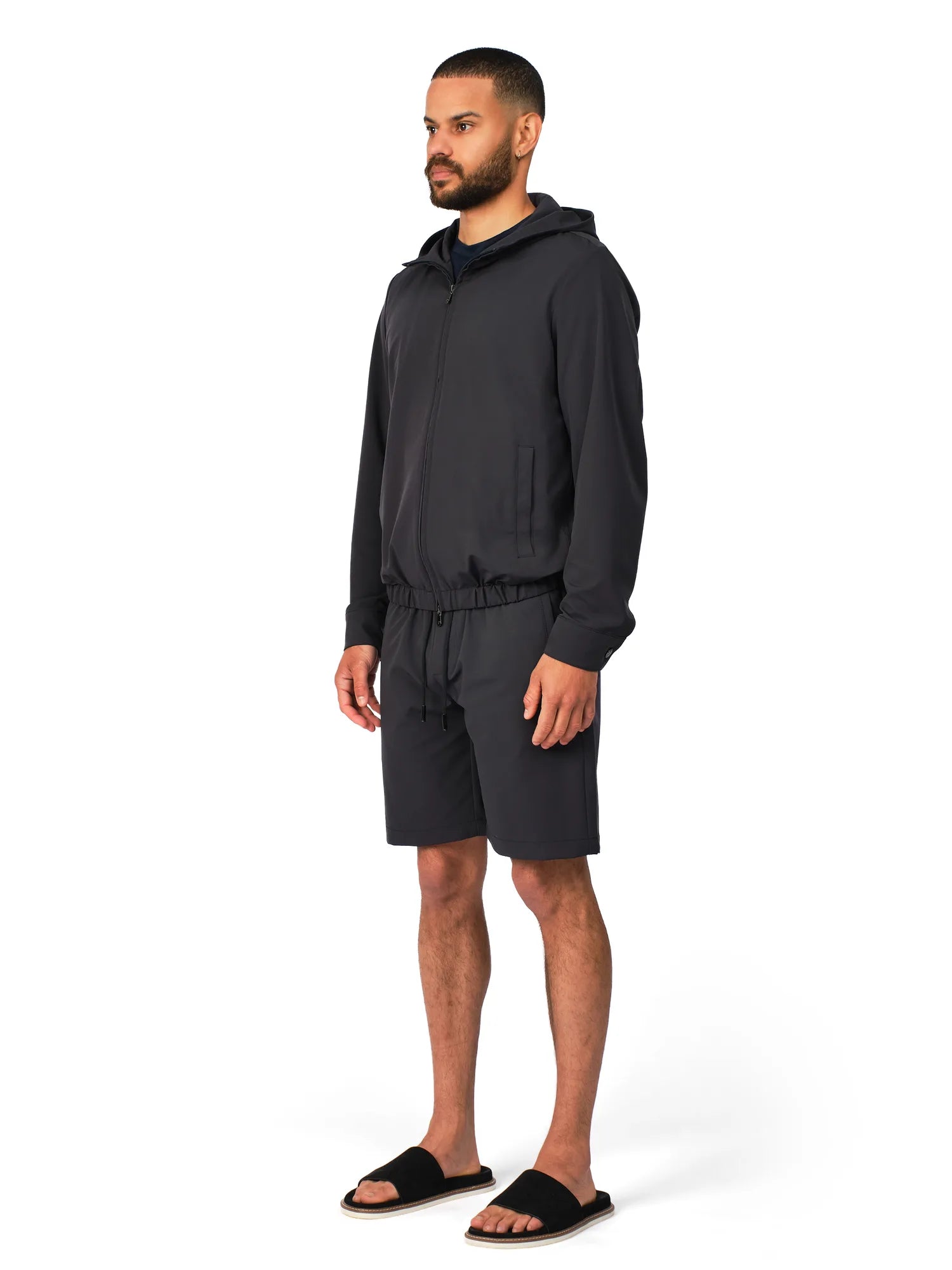 Man wearing a black hoodie and shorts set on a white background